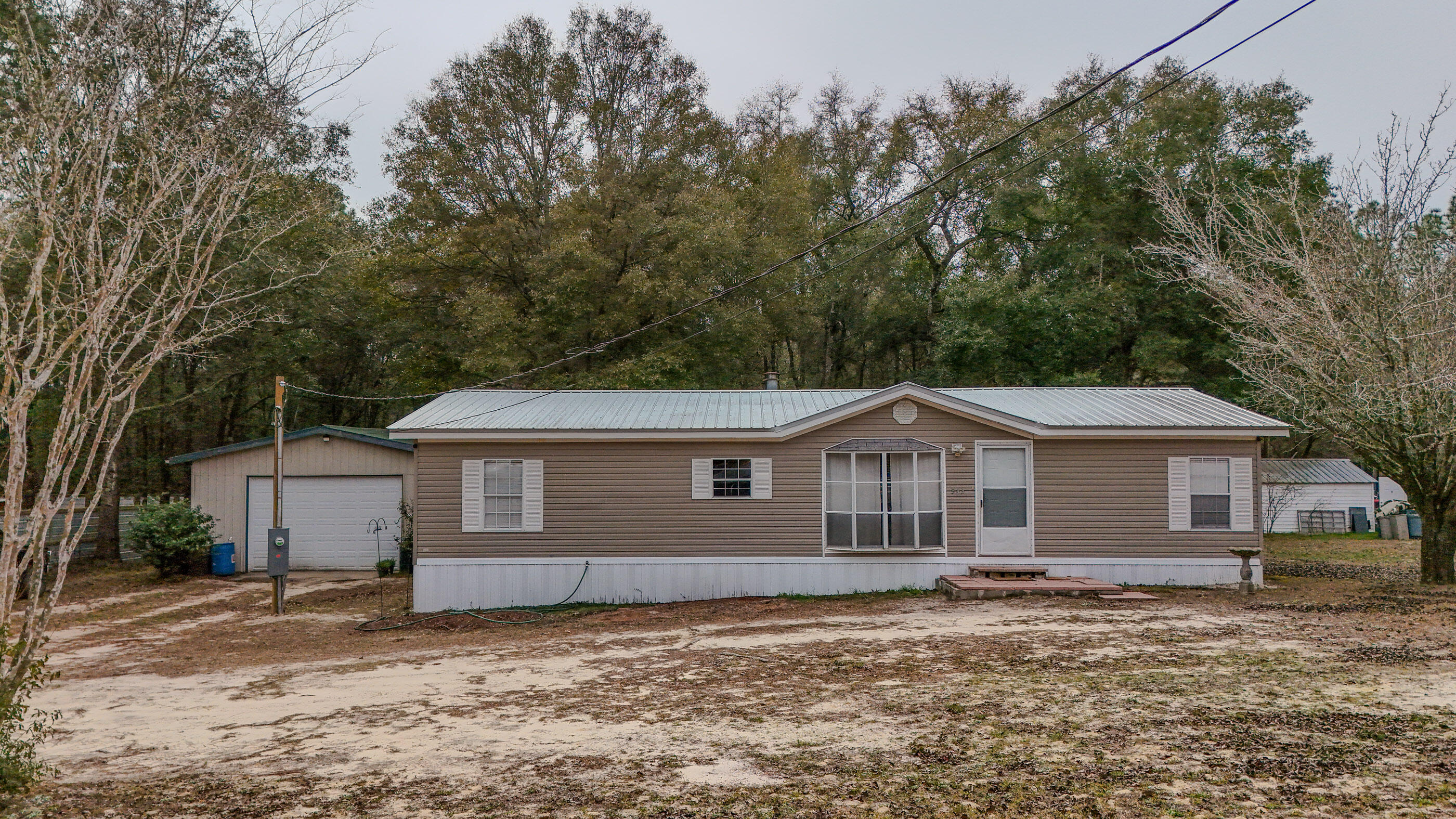 Seller offering $5,000 flex money to buyer! Welcome to 543 Cat Island Rd—a 3BR/2BA manufactured home offering 1,404 SqFt in a great location to Defuniak Springs, wooded setting near Lake Juniper. Enjoy easy country living with a metal roof, a metal shop, and a spacious rear deck—perfect for grilling, relaxing, or entertaining.

Inside, you'll find a comfortable, open living area with wood-look flooring and a fireplace, plus a bright dining space that flows into the kitchen. The kitchen features ample cabinetry, generous counter space, and a functional layout for everyday living. The split-bedroom setup provides privacy, and both bathrooms offer practical finishes including a tub/shower combo.

Need space for projects, storage, or hobbies? The property includes a large metal shop/garage with a roll-up door, work area, and cabinet storage ideal for tools, toys, or weekend tinkering. If you're looking for room to spread out and enjoy the outdoors while staying convenient to town and the lake area, this one is a must-see!

Buyer to verify all information deemed important.