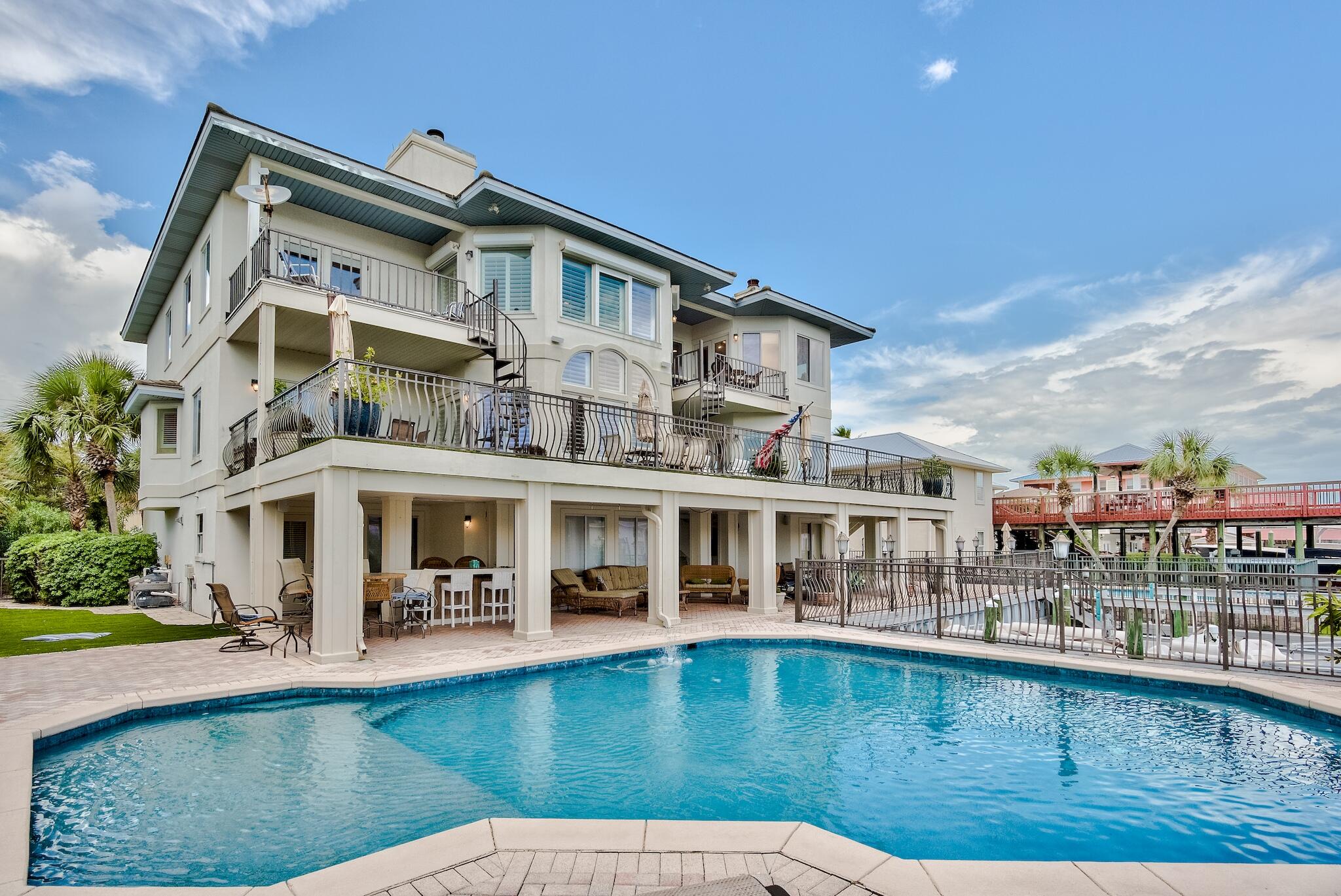 A rare opportunity for 6,800 square feet of Destin Harbor allure with exceptional views, two boat slips, private pool, and spectacular outdoor living space. This six bed, five bath masterpiece boasts an impressive rental repertoire, set to exceed $220K in gross income this year. Enter the stately white facade with lush tropical landscaping to a light-filled, open retreat, equipped with every modern convenience. The backyard covered patio spans across the length of the house, opening to the private 30 x 25 ft pool, whirlpool, and sun deck. A dock sits ready with two boat slips, one with a powered pontoon lift, and dockage along the seawall, accommodating three vessels up to 52 ft in length. A second level artificial turf covered patio offers breezy sunset views from the relaxing waterfront oasis. You'll find endless luxury at 512 Osceola, including an elevator, gourmet kitchen, formal dining room, spacious bedroom suites, a game room, garage parking for four cars, and private balconies. This turn-key property on Holiday Isle is offered fully furnished, equipped with an 8 passenger golf cart for the 3-4 minute ride to the beach, and pontoon boat for an easy cruise to Crab Island.