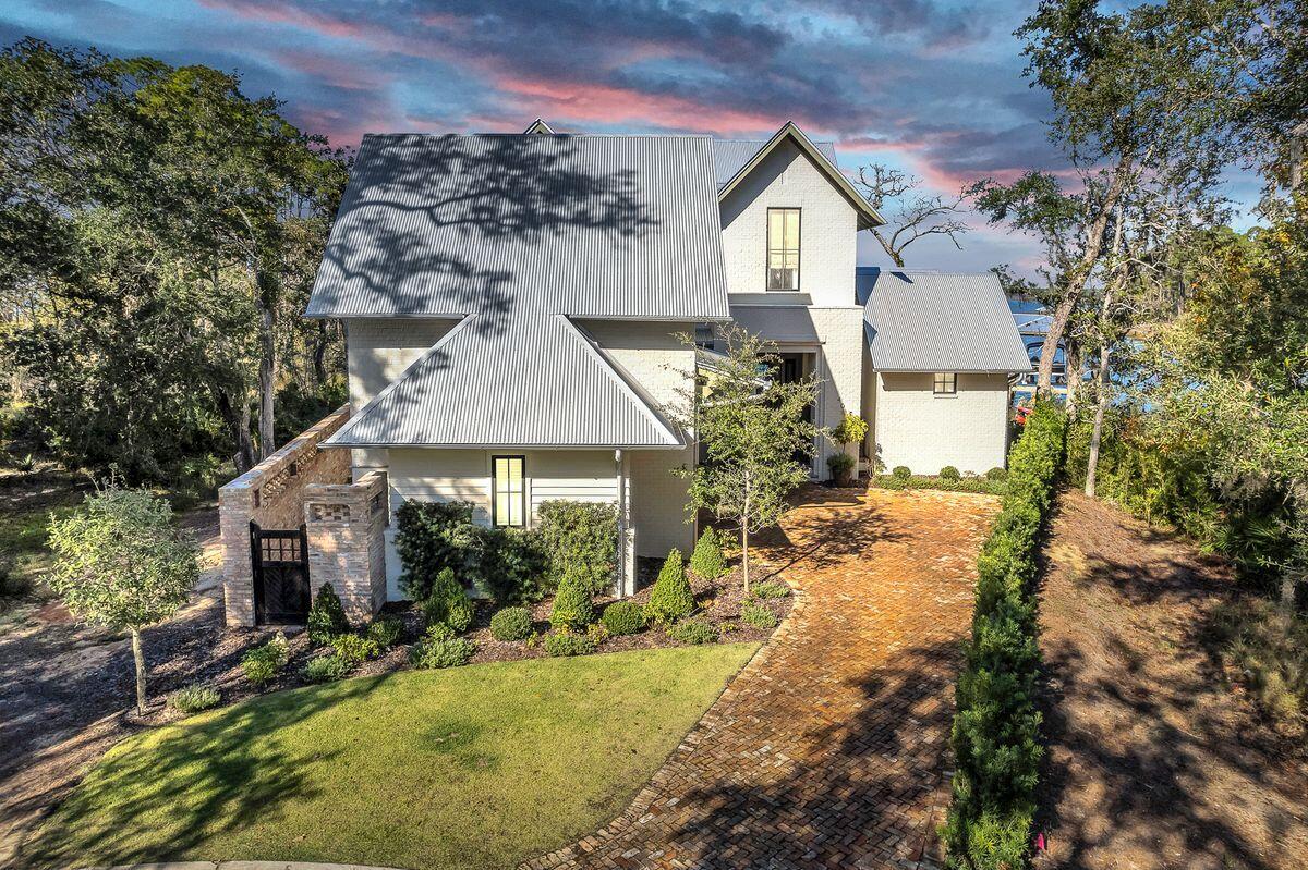 Designed by architect Matt Savoie and built to the highest standards by Custom Coastal Builders' Tim O'Hara, this exceptional Bayfront home is one of just four in Churchill Oaks to have a private dock. This beautiful home offers 150 linear ft of bayfront and boasts a synergy of design blending the interior and exterior colors and textures with the magnificent views of the bay & bayou. Distinguishing features include beams reclaimed from an old Mississippi barn, built-in bookshelves, custom cabinetry, and floor-to-ceiling impact glass sliders with auto-blinds in the living room. Parisian doors from the 1600s announce the entrance to the elegant powder room and the laundry, It's craftsmanship at its very best. The magnificent primary bedroom on the first floor has vaulted wood ceilings, with a sitting area overlooking the unprecedented views of the bay and a spa-like bathroom. The gourmet kitchen has everything on your wish list: Wolf and Sub-Zero appliances, a double oven, a six-burner griddle stove, and much more. Move into the bar area where guests are welcomed with cocktails served to perfection from the wine column, beverage cooler, and ice maker, a perfect place for entertaining. Enjoy unmatched outdoor living in the lovely courtyard paved with authentic Chicago brick an outdoor kitchen and privacy wall make this an idyllic spot for intimate family barbecues or entertaining al fresco. The saltwater pool creates a beautiful centerpiece, thrilling all the senses with its starlight bottom, bench seat, and fountain element. Step off the porch and enjoy outdoor living at its finest as you relax around the fire pit with a glass of wine at sunset overlooking your own private dock. The home conveys with an almost new pontoon boat for enjoying, fishing, and summers on the water. The 1-bedroom 1-bathroom carriage house has a completely separate entrance that is currently used as an office/bonus space. Additional features include a whole-home generator, weatherproof decking, Jeld-Wen double-pane windows, and tankless water heaters. The exclusive gated bayfront community of Churchill Oaks offers a lifestyle of elegance and appreciation of nature.  The bayfront Clubhouse is an unmatched 8,000 SF amenity with 3 large pools, an outdoor bar, a commercial-grade kitchen, large gathering spaces, a fully equipped media room, an exercise room, and a locker room, all for owners and their guests to enjoy.