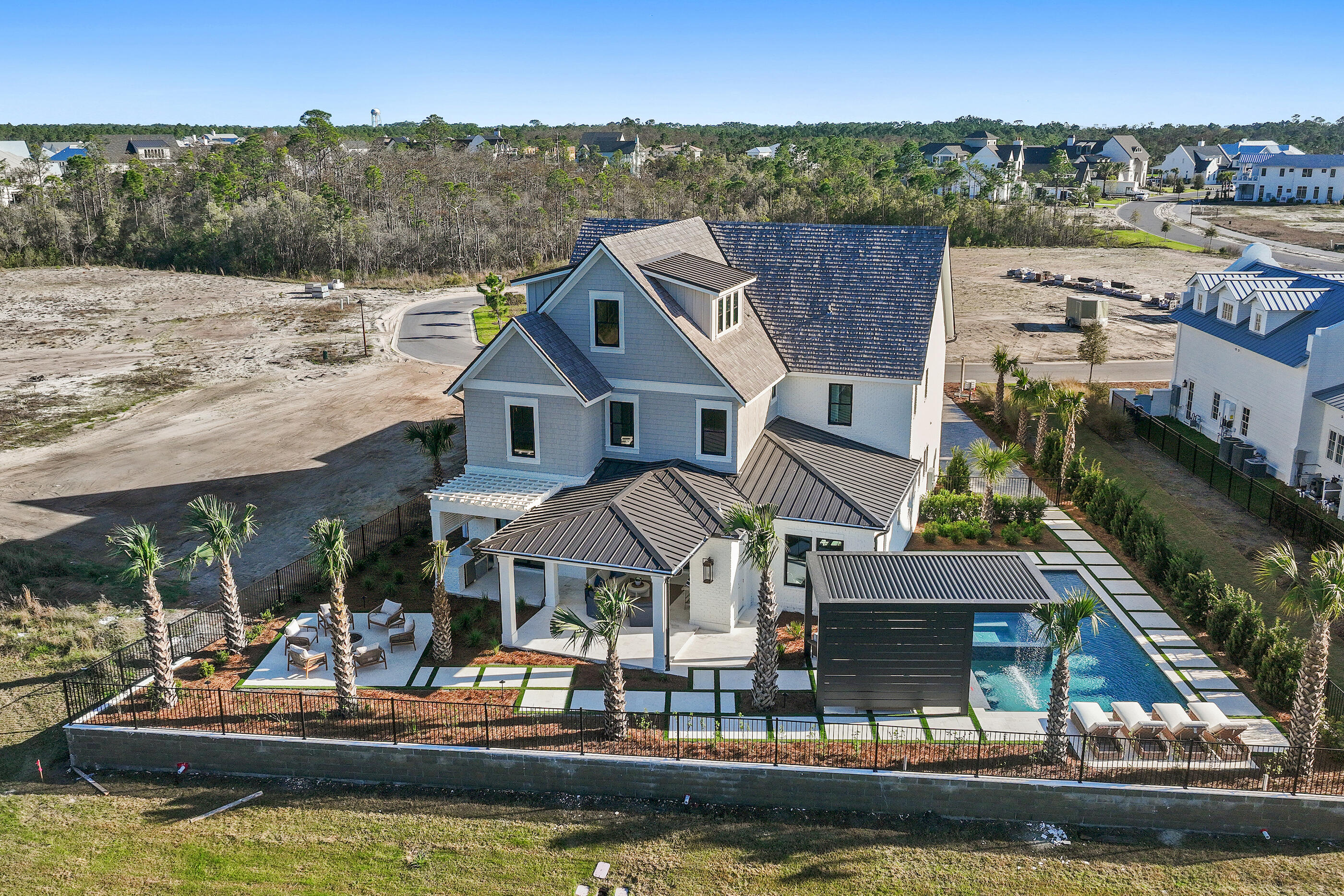 There is something inherently calming about life at the edge of water--and at 49 Sundew Place, that rhythm becomes part of the everyday. Set within the gated community of WaterSound Camp Creek and backing to a peaceful pond, this newly built residence spans 5,549 square feet across three beautifully finished levels, offering five bedrooms, five full bathrooms, and three half baths in a home designed for both comfort and elevated coastal living. One of the distinct luxuries of Camp Creek living is the inclusion of a WaterSound Beach Club membership, extending the experience beyond the home to Gulf-front amenities and a refined coastal lifestyle. Inside, natural light moves easily through spaces framed by white oak tongue-and-groove ceilings and coffered architectural detailing, creating an atmosphere that feels refined yet relaxed. The main living area is anchored by a fireplace and custom built-ins, forming an inviting setting for quiet mornings or evenings that unfold slowly with conversation and coastal breezes.

The kitchen balances craftsmanship and warmth, featuring custom cabinetry, Sub-Zero appliances, and a built-in coffee station, alongside a thoughtfully designed scullery and butler's pantry that keeps entertaining seamless. Just beyond, a temperature-controlled wine cellar offers a refined space for collection and celebration alike.

Outdoors, the home transforms into a private retreat. A heated pool with waterfall, spa, and fire bowls creates a striking focal point, while a swim-up bar adds a resort-inspired touch. The poolside cabana, complete with a distinctive rainfall feature roof that opens to the sky, offers a shaded place to unwind between moments in the sun. Nearby, the outdoor kitchen and fire pit set the stage for evenings that stretch long into the night.

The primary suite is designed as a quiet sanctuary, featuring a spa-inspired bath with sunken shower, soaking tub, dual vanities, and thoughtfully separated spaces that allow for both privacy and ease. Upstairs, ensuite guest bedrooms offer comfort and privacy, while a **generous media lounge with wet bar--easily convertible to an additional bedroom--**creates a flexible space for movie nights, gatherings, or extended accommodations. A third-floor flex space--ideal as an office, creative studio, or additional lounge--adds yet another layer of versatility.

Modern conveniences include multiple laundry rooms, surround sound throughout the interior and outdoor living spaces, and a three-car garage designed to support everyday living with ease.

Blending thoughtful design with the tranquil beauty of its waterside setting, 49 Sundew Place offers a home where architecture, lifestyle, and a sense of place come together effortlessly within the distinctive landscape of Camp Creek. Professionally staged by the team at Lusso Interiors, with turn-key furnishing packages available for purchase--outdoor loungers, fire-pit chairs, and pergola furniture are offered with the sale. Inquire today and discover the coastal lifestyle this home so beautifully represents.