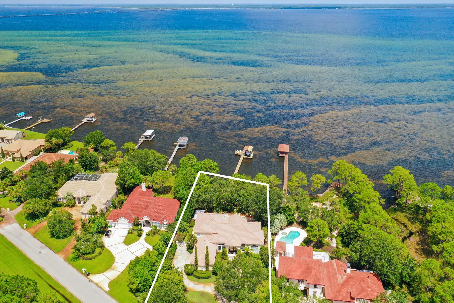 The epitome of waterfront living perfectly poised on a private estate sized lot (.88 acre) yielding an impressive 115' of premium water frontage on the Choctawhatchee Bay. This beautiful four bedroom retreat has been meticulously maintained with notable features including ample privacy created by lush mature landscaping, new hardwood flooring throughout the first floor, fresh interior and exterior paint, first level master suite and an expansive 45x25 private bay-front pool presiding over endless water views. Sprawling mature landscaping coupled with mediterranean architecture define the extraordinary sense of arrival upon entering the property through one of two private driveways that allow direct access to circular parking for guests or access to an oversized two-car garage with an additional bay suitable for a golf cart. The front entryway is encased with floor to ceiling glass allowing for immediate water views and characterized by soaring double height ceilings that extend into the formal living room just beyond the elegant winding stair case with freshly painted banister and natural oak stair treads. The first level offers two primary living areas with a spacious kitchen anchoring the open floor plan allowing direct access to the living & dining area with extensive water views through floor to ceiling glass windows extending the entire length of the north facing elevation. The finely appointed kitchen yields ample custom cabinetry with white solid surface countertops for a clean coastal aesthetic as well as an electric cooktop in the center island which allows for beautiful bay views while preparing meals. The first level also offers a formal dining area and a home office that could be utilized as a fifth bedroom space. The rear yard and covered porch offer an unrestrained coastal lifestyle with every amenity desired including a massive resort style pool area, outdoor covered grilling area, oversized pool deck complete with loungers and an exceptional variety of foliage maintained to maximize serenity and privacy. The dock in place is complete with boat slip and lift as well as a sitting area which is directed towards the northwestern sunset vista. The master suite occupies the entire eastern wing of this beautiful home and yields two walk in closets, sitting area with direct access to the covered rear porch and pool area as well as an impressive ensuite bathroom complete with dual vanities, floor to ceiling windows looking out towards the garden, jacuzzi tub, walk in shower and private water closet. Other notable features include three bedroom suites with ensuite bathrooms located on the second floor, two of which are located directly on the bay with a private balcony overlooking the water and private grounds. Emerald Bay is a gated neighborhood centrally located in Destin, FL offering a premier golf community and easy access to world class shopping, dining and entertainment.