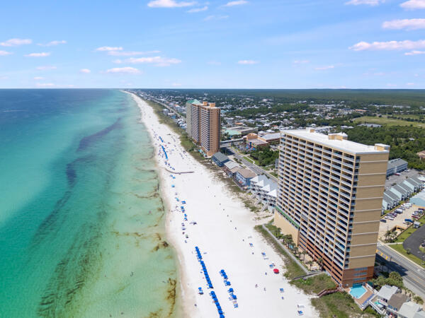 Welcome to Tropic Winds 1806, a stunning Gulf-front condo offering breathtaking views, strong rental opportunities, and the ultimate Panama City Beach lifestyle.  Perched high above the sugar-white sands, this beautifully positioned unit delivers panoramic Gulf views from the living area, primary bedroom and private balcony- perfect for sunsets, morning coffee and coastal entertaining.  Inside, you'll find a bright, open-concept layout designed for comfort and functionality.  The living and dining areas flow seamlessly into the kitchen, creating a welcoming space for gathering after a day at the beach.  Floor-to-ceiling windows and sliding glass doors flood the unit with natural light and showcase the endless Fulg views that make beachfront living unforgetable.