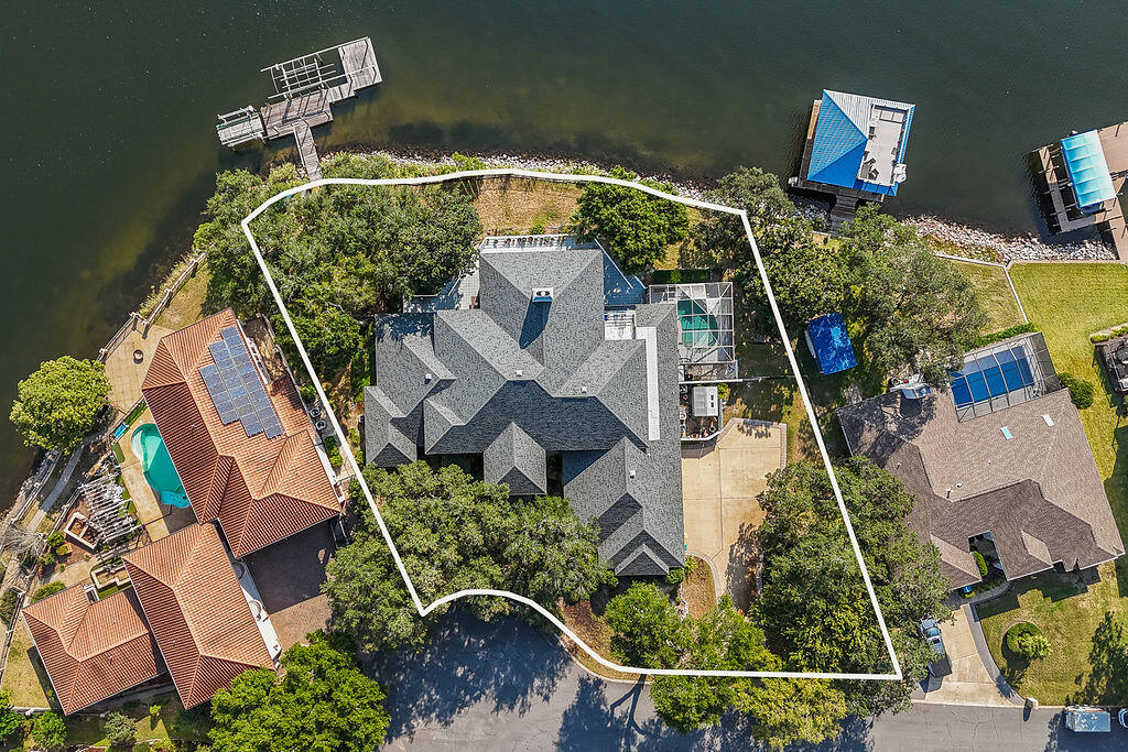 Back on the market through no fault of the seller — buyer financing issue. Welcome to your waterfront estate! Located on a double lot in the coveted Lake Pointe neighborhood with 180' of breathtaking waterfrontage, this magnificent residence is more than a place to live; it's a way of life! High and dry in the harbor of Lake Lorraine, with direct access to the bay, this home offers both safety and serenity! Upon entering, you'll be captivated by the sheer size and elegance of this home. Boasting five bedrooms and four and a half bathrooms, this residence offers ample space for family and guests. The primary suite is a sanctuary of its own, featuring serene water views, a private deck, and a luxurious en-suite bath with all the desired amenities.