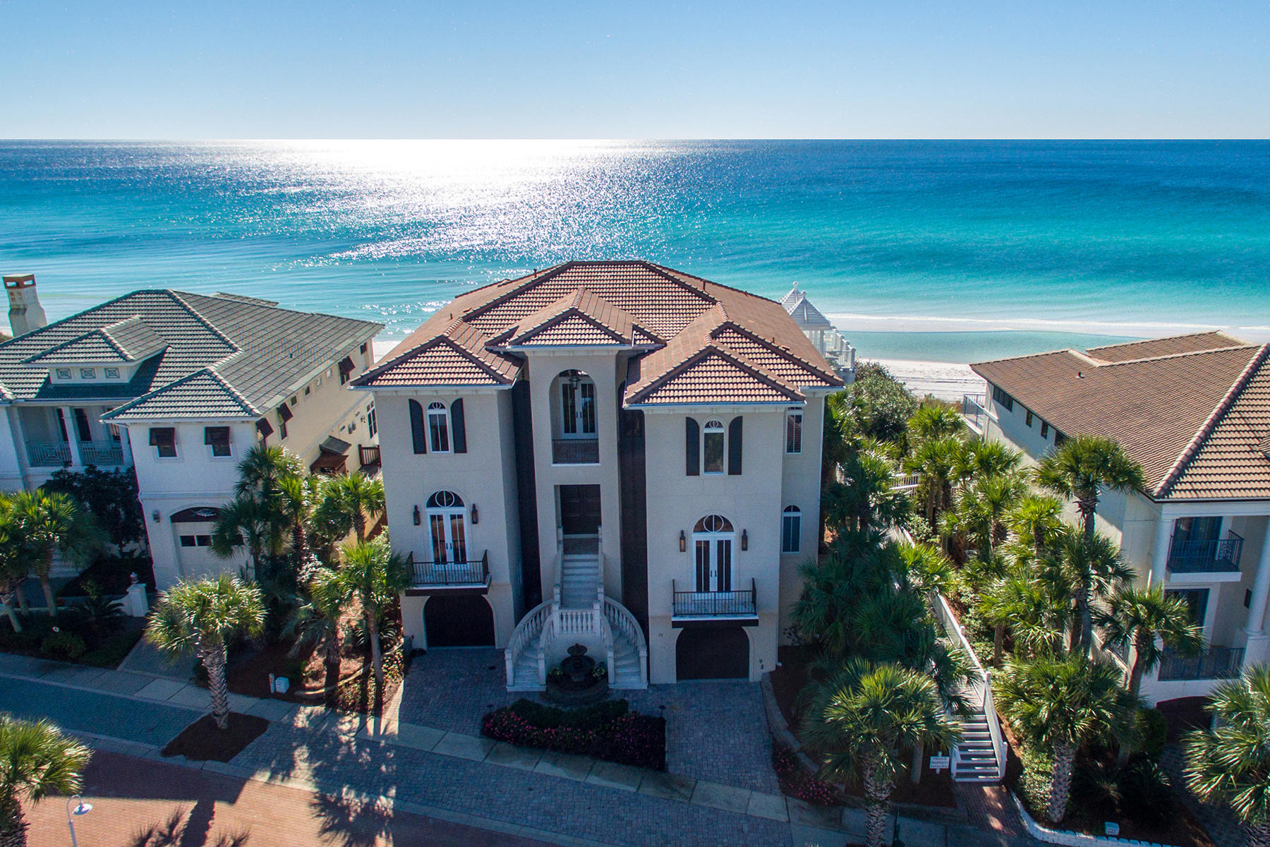 This one-of-a-kind home enjoys a prime gulf front position within the gated Village of White Cliffs community. Recently redesigned and redecorated with no expense spared, this three-story home is among the highest elevations along the Gulf Coast and takes advantage of the expansive gulf views Protected by a contiguous seawall buried in the sand dunes, this home is an architectural showcase with Anderson windows, marble staircase, twisted columns, as well as barrel, dome, and groin vault ceilings providing an aura of upscale design throughout this magnificent residence. The new owner can enjoy all the trappings of a luxury lifestyle with custom theater, game room and guest suite nestled into the dunes. The great room with 12 foot coffered ceilings offers two seating areas, gas fireplace with walnut mantel ensemble with art niches. Retractable art conceals the flat screen TV when not in use. The island kitchen continues with the highest standards of design and modernity. Appliances include a SubZero Refrigerator, wine fridge, gas range, and 2 Dacor convection ovens with warmer drawers for entertaining. A breakfast nook adjoins the kitchen overlooking the Gulf and a separate dining room features a classic domed ceiling. Each of the six bedrooms has its own private en-suite bath featuring hand-tumbled tiles, polished travertine stone and solid stone surfaces. The third floor is largely given over to a grand and luxurious master suite with morning bar, his-and-hers walk-in closet, laundry room, and a large covered terrace with panoramic gulf views. The adjoining bathroom would not be out of place in any spa with twin vanities, a jetted tub and two adjoining rain showers. Behind the scenes, this two-garage home is wired for a customizable smart system and boasts four air-conditioner units and central vacuum. The uniquely wide 75 ft wide lot extends to the beautiful sandy beach with room for a pool, once current DEP approval has been finalized.