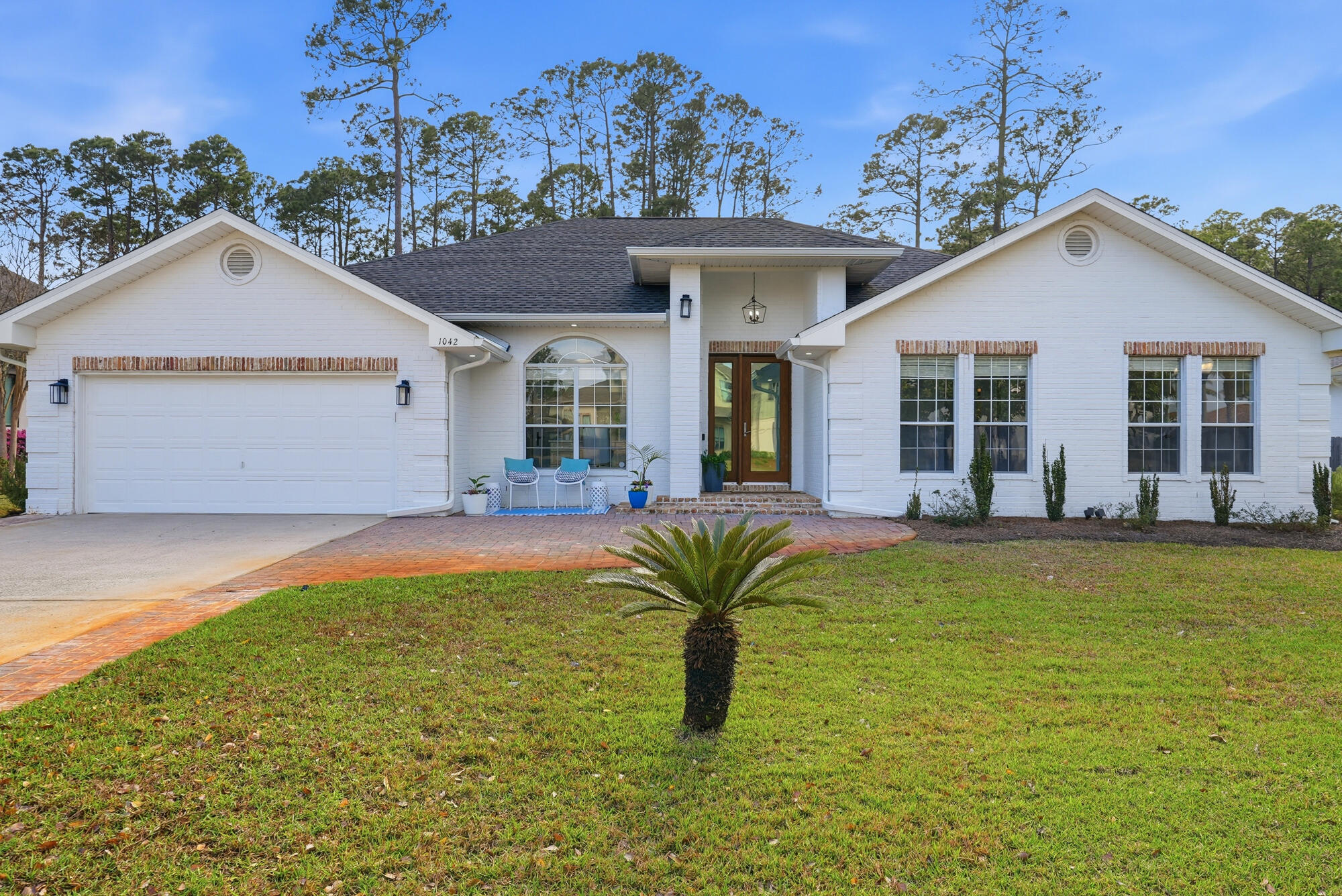 Beautifully remodeled custom home in Driftwood Estates with timeless curb appeal and upscale finishes throughout. The painted brick exterior, brick paver entry, and custom wood double front doors create an inviting first impression. Inside, enjoy a chef's kitchen with waterfall quartz island, full slab backsplash, custom cabinetry, wine refrigerator, pot filler, and a premium gas range. Open living features wide-plank tile flooring, shiplap accents, tray ceilings, and designer lighting. A private home office with built-ins and glass French doors adds flexibility. The primary suite offers a spa-style bath with soaking tub and oversized shower. Large pantry, custom laundry room, and a private backyard with mature trees complete this move-in-ready home near South Walton beaches. Completely remodeled and shows like new construction. High-end details throughout including custom cabinetry, quartz countertops, full slab kitchen backsplash, waterfall island, wine fridge, pot filler, and ZLINE gas range with statement vent hood. Dedicated home office with custom built-ins and French doors, perfect for remote work. Spa-inspired primary bath with freestanding tub and oversized walk-in shower. Thoughtfully designed pantry and laundry room with sink and storage. Private backyard with mature landscaping.