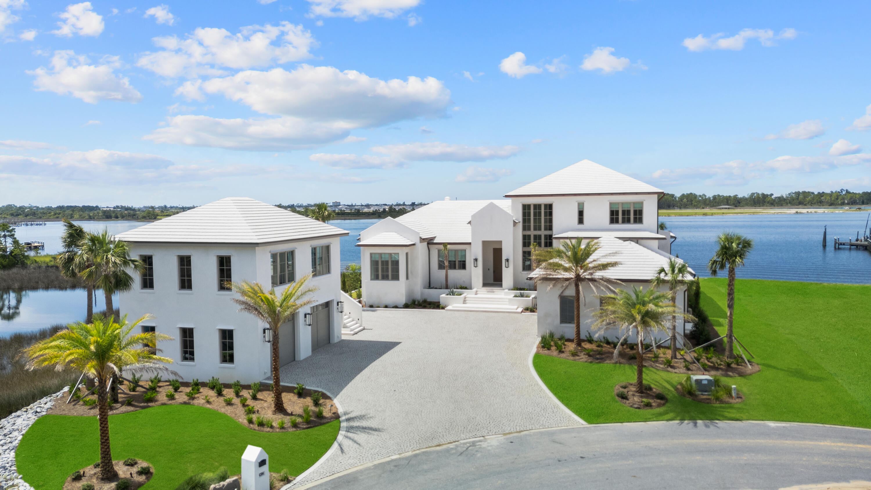 This is a WATERFRONT home that transcends expectations and delivers privacy over prestige—exuding quiet, effortless luxury. Tucked away on a private island of 381' of shoreline in Panama City, Florida, this 2025 newly constructed residence is more than just a home...it's a legacy. A rare blend of architectural brilliance, natural beauty, and elevated craftsmanship, this estate redefines coastal living. Designed by Wes Seaborn, built by McIntosh-Myers Construction, and curated by Lori Faison Interiors, every element was intentionally crafted to support a lifestyle of beauty, comfort, and refinement. 

The design is rooted in organic minimalism, elegant in simplicity, yet rich in warmth and texture. A 12' impact-rated mahogany door opens to a soft palette of Venetian plaster, shellstone, and white oak select throughout. Light dances across barreled plaster hallways with fused-in lighting beneath. It's a quiet symphony of detail. Subtle, yet unforgettable. The vaulted living room is clad in white oak select with a fluted plaster fireplace and Nano doors that open to a sprawling covered lanai. The adjoining dining room, wet bar, and open kitchen invite gatherings, centered around paneled SubZero and Miele appliances, concrete countertops with fused-in sinks, and custom EF San Juan cabinetry. A remarkable scullery and discreet storage keep the space functional yet clean, perfect or entertaining or daily life. 

Spanning 5,364 SF of heated/cooled space and 8,543 SF under roof, the main residence exudes a highly desirable floorplan. All bedrooms enjoy breathtaking panoramic water views. Offering seamless Gulf access just 10 nautical miles away, without idle zones slowing you down and pure Bay views. At 14' elevation and built of poured solid concrete, this home is as resilient as it is beautiful. 

The private primary suite is its own tranquil escape, accessed through a barreled, Venetian plaster backlit hallway. Inside, you'll find motorized drapes, a beverage fridge, and a steam shower and soaking tub that will take you straight to the spa. Step through to your private lanai and fireplace for pure relaxation. 

With four spacious bedrooms, four full en suite baths, and two half baths, there's space for hosting without compromising privacy. A dedicated home office wrapped in oak and plaster, oversized laundry with dual washers/dryers, and a thoughtful mudroom with custom lockers make daily routines effortless. Step outside to the covered lanai and unwind by the outdoor fireplace or summer kitchen. The negative-edge pool is a work of art fused with design. Custom tile-lined, stone-surrounded, and built with a chiller/heater, trough-style drains, and no skimmer for a clean, seamless finish. 

But the performance is just as impressive as the design. Featuring a 4-car garage and built atop a two-way slab, the structure features poured CMU block, a concrete roof, copper gutters, Andersen impact-rated windows/doors, and a reinforced safe room with poured concrete and rebar. A 500-gallon buried propane tank powers key systems, supported by three HVAC units, three tankless water heaters with circulating pump, a generator-ready transfer switch, and a deep irrigation well. 

Every detail reflects a level of quality rarely seen, fused-in window and baseboard trim, concealed backlit air returns, modern custom Boyd lighting, solid concrete countertops, and custom 8' solid doors. The Lutron lighting system offers full customization for every mood and moment. For future expansion or guests, the detached carriage house provides 830 SF of space already roughed in with plumbing and electrical, ideal for a guest loft, art studio, or wellness retreat.

This is more than a residence. This home is a legacy. It's a peaceful sanctuary where design meets intention, where the only thing more breathtaking than the architecture is the view. If you've been searching for a home that's as extraordinary as the life you want to live, you've just found it.