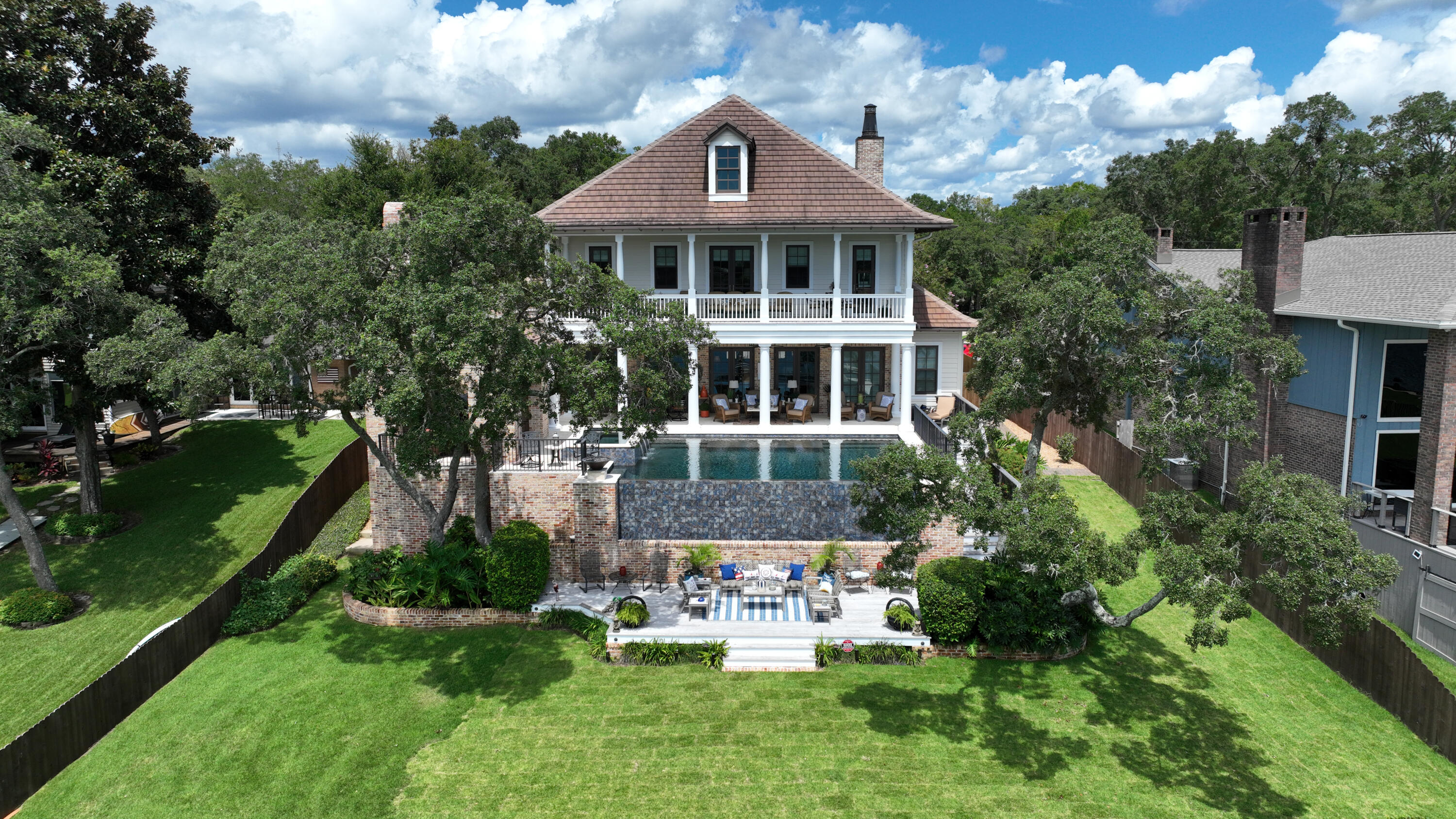 This stunning waterfront home is an architectural masterpiece! From the second you drive up the quality and details are impossible to overlook. Stepping into the beautiful plantation-style brick home you're immediately met with a warm character from features including incredible wide plank reclaimed heart pine flooring, wood beams, a gas fireplace with surrounding built-ins, and a wrought iron staircase. A wall of doors and windows allows for breathtaking views of the infinity pool and waterfront. The gourmet kitchen is top-of-the-line with Thermador appliances, a sub-zero ice maker, and beverage cooler, custom cabinets with glass fronts, beautiful granite countertops, and a large center island with a breakfast bar. The open-concept dining area is an entertainer's dream with two built-in buffets. The waterfront master suite has private access to the pool and spa, a separate bath with double vanities, a spa tub, a large steam shower, a separate walk-in closet, and a make-up station or office area. Ascending the staircase you will find a free-standing walnut piano curved overlook perfectly appointed as a sitting area with shiplap walls and French doors that lead out to the front balcony. You'll also find two additional bedroom suites and a spacious study or entertainment room with custom built-in heart pine cabinets, surround sound, and a wet bar with a subzero beverage refrigerator. The entertainment room and one of the guest suites are waterfront and each has private access to the expansive balcony with incredible water views. Your resort lifestyle awaits you in the backyard with a custom-designed heated infinity pool with a tanning ledge and spa surrounded with coral stone pavers for cool decking and two fire-pots for ambiance. Imagine entertaining family and friends year-round in your outdoor brick cabana with a fireplace, media and surround sound. Outdoor kitchen with Naturekast cabinetry, Lynx and Fire Magic appliances include gas grill, sink, warming drawer, separate gas burner, and beverage center, Brazilian hardwood deck, and plenty of counter space for parties of any size you host. Get ready for fun on the water with your private dock complete with a covered boat house with a 20,000lb lift, a 10,000lb boat lift, and two jet ski lifts to go out and cruise the bayous, bay or head out to Crab Island for fun in the sun. This incredible home is worth experiencing!