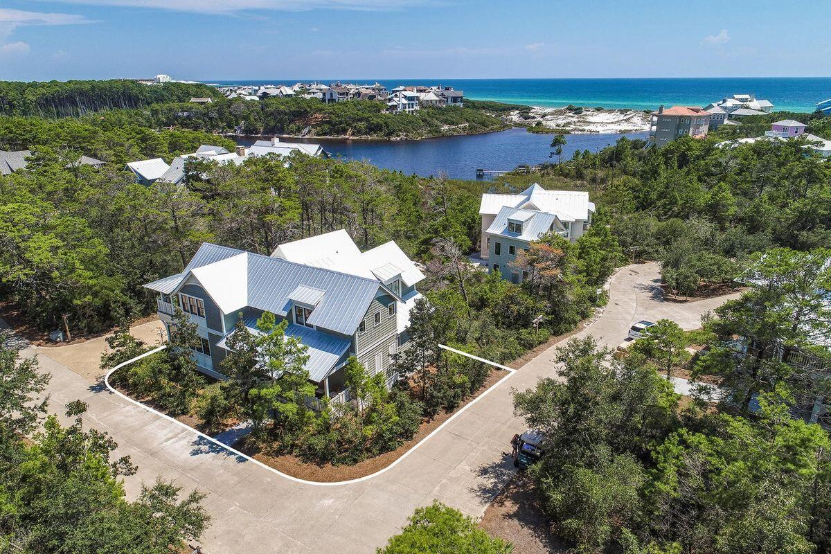 This delightful home and accompanying carriage house sit on a picturesque corner lot in the rental-restricted community of Draper Lake Coastal Village. The Village is located on the highly desirable south side of scenic Highway 30A. The house has three large porches; two of the porches provide private settings with lake breezes and peek-a-boo views of the lake, white sand dunes, and the ocean. The front porch offers a perfect perch for meeting, greeting, and visiting with neighbors.  Stepping inside, the open floor plan is designed to provide a complete first-level living experience. The first floor contains a generous sized kitchen, dining area, a family room, half bath, laundry room, screen porch, as well as the primary bedroom with a well-appointed en suite bath and a very large walk-in closet. The family room has double French doors that open to a screened porch which runs the full length of the house thereby providing room for an oversized swing, two sitting chairs and an outside dining area. Upstairs there are two large bedrooms with spacious closets, a full bath, and a charming landing that can serve as an office or sitting area. One of the bedrooms is currently used as an exercise room that features a padded floor and mirrored wall with ballet bars. The other bedroom contains a sitting area with double French doors that open to another porch that runs the full length of the house. The property also has a detached carriage house that is located over a large two-car garage.  The carriage house has a living room, separate bedroom, full bath, porch with gulf views, laundry hookup, mini-fridge, and microware.
Beach access is available via boat or a short two-block walk from the home. Less than a half block from the land access point, the Draper Community owns an exclusive "beach cabana" that provides Draper residents with gated parking, private showers, and clean bathrooms. Inside the neighborhood there are two pools, two parks, and a 45' Observation Tower. Two boathouses have second floor sitting areas that offer stunning lake and Gulf vistas. The boat houses also provide storage for paddle boards, kayaks, and canoes. Launch points can be found not only from the boathouses but also along the nature paths that wind all along the lake and throughout the community. A protected 100-foot buffer along the lakefront ensures conservation and enjoyment of the lake by all residents. The unique architecture of the houses, abundance of Southern live oak trees, and the preservation of natural plants provides a peaceful oasis rarely found in beach communities. Located in the lively Blue Mountain Beach area, you'll have convenient access to a host of beloved restaurants and shops, as well as nearby attractions in the Gulf Place, Grayton Beach, WaterColor, and Seaside communities. For a complete portrait of Draper Lake Coastal Village please visit www.discoverdraperlake.com.