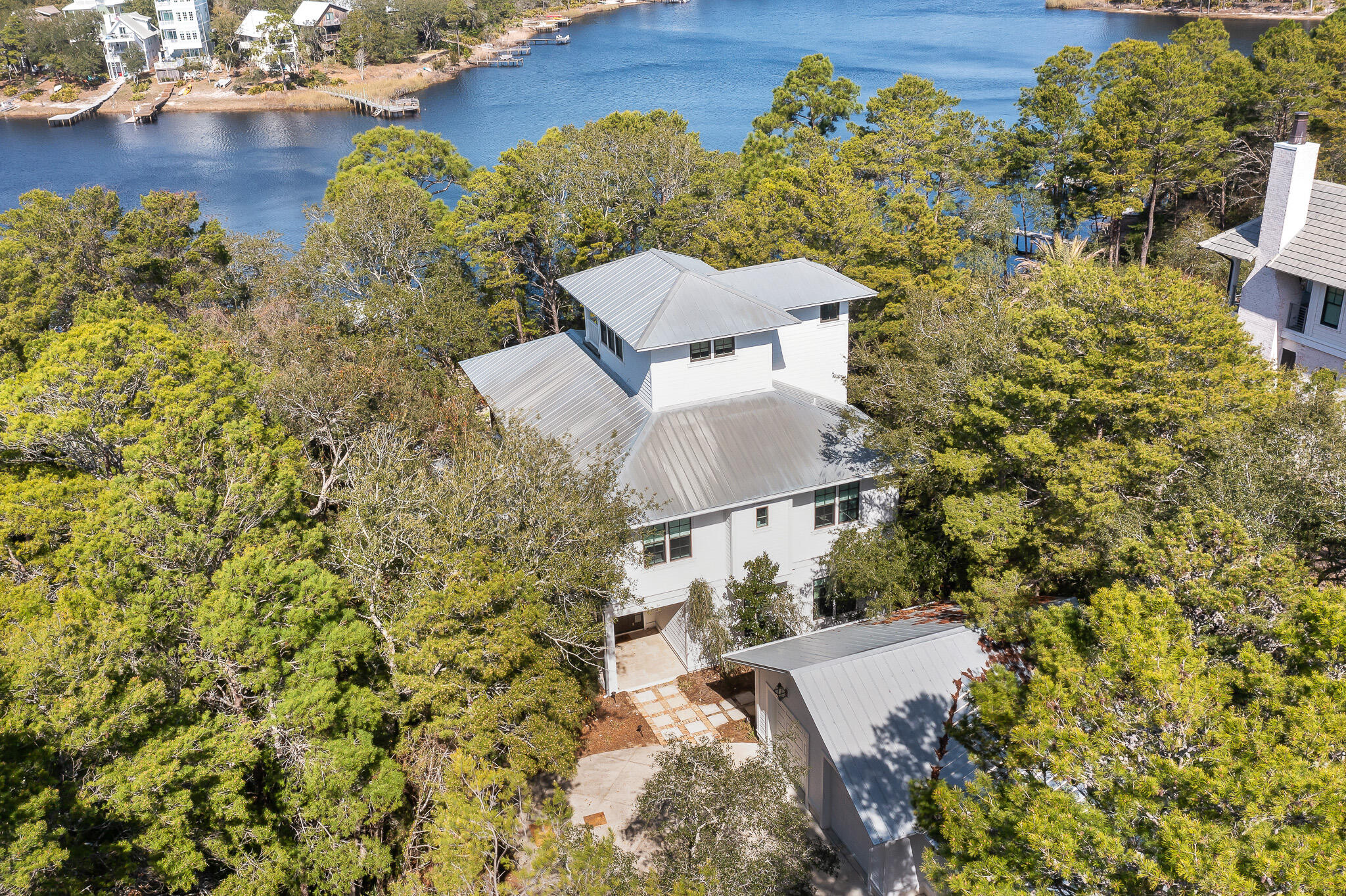 Under contract, accepting back ups. This lakefront home on the coastal dune lake of Camp Creek Lake is nestled among nature on one of 30A's rare and special streets, along the desirable east end of 30A. Designed by the prominent local architect Walt Chancey with Chancey Design, this special lake retreat boasts an idyllic setting with breathtaking views of Camp Creek Lake.  The unique location gives you a peaceful sanctuary among the trees, while being just a mile from Alys Beach. The bustling liveliness of 30A's surrounding popular planned communities are all in close proximity, giving the enjoyment of dining, shopping and events all within a short bike ride from your quiet haven. Characteristic of the rare coastal dune lakes is the outfall connection of the lake directly with the Gulf. Canoe or paddleboard to the beach right from your private dock.  Take in a new routine of laid-back living, gathering on the deck, and nightly sunsets on the dock. Upon entering the home, you are greeted with an open living and dining room, aligned with a screened-in patio, with large gathering spaces and an outdoor summer kitchen. Two 12-foot sliding doors open for indoor and outdoor entertainment, as well as doubling the living spaces and fully embrace the majestic lake life. Dark stained white oak floors lead to a gourmet kitchen, showcasing all Viking appliances, two dishwashers, concrete countertops, and a spacious walk-in pantry.  An adjacent dining space features a candlelight chandelier and stunning lake views.  Step into a sunken living room with towering ceilings, custom lighting and a real wood fireplace. A private guest bedroom and bathroom is located on the first floor as well. The second-floor primary suite opens to an enclosed patio overlooking the lake, with a sitting area perfect for morning coffee or sunset views, as well as an expansive walk in closet and primary bath with freestanding tub. The second floor also features two additional guest bedrooms and a flex space perfect for a home office or two sets of bunk beds. The third floor is encompassed with a spacious bonus room and sun deck; soaring above the trees with panoramic views of the Emerald Coast and WaterSound community. Custom seating surrounding a fire pit with an Old Chicago brick courtyard accompanies a hardwood deck on the back of the house, as well as a dead head cypress kitchen with refrigerator, grill and sink. This home also includes a large dock with dining table and built in benches. Escape to 117 S Camp Creek Road, a perfect balance of refinement, elegance, and a coastal lake lifestyle.
