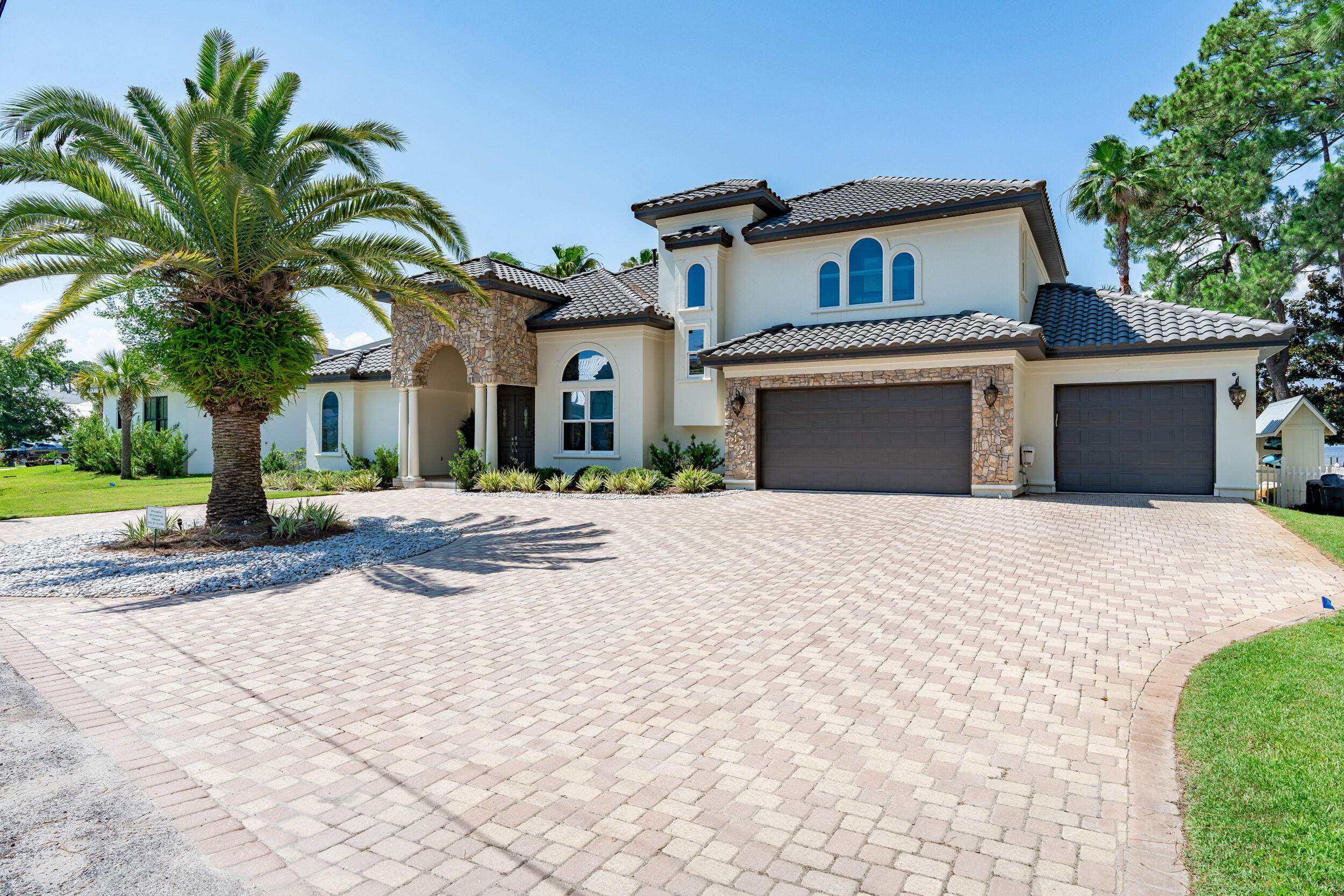 Listed below a recent appraisal, this stunning property includes a pontoon and jet skis for ultimate waterfront living.Welcome to 136 Casa Grande Lane, an exquisite Mediterranean-style residence that seamlessly blends luxury with the serenity of bayfront living. Situated on an expansive ½ acre lot, this home offers unparalleled sunset views over the tranquil bay, creating a picturesque backdrop for your daily life. Designed as an entertainer's paradise, the property features a screened-in lanai that overlooks a backyard oasis complete with a putting green, a custom firepit, and a private dock and boathouse. The boathouse comes equipped with a Pontoon and jet skis, all with convenient lifts, and even includes a mat off the dock for practicing your golf drives into the sunset.
Step inside to discover a home where elegance and comfort meet. The living room is a cozy retreat, with a gas fireplace flanked by built-in bookcases adorned with beautiful tile accents. Adjacent to this is the formal dining room, featuring a built-in wine nook that is perfect for hosting intimate dinners. The gourmet kitchen is a chef's delight, boasting detailed cabinetry, a stunning backsplash, and a quartzite breakfast bar. The paneled refrigerator blends seamlessly with the cabinetry, giving the kitchen a custom, polished look, and a built-in desk adds convenience for your daily routines.

The primary wing is a true sanctuary. It includes a private fireplace, built-in cabinets, and a sitting area that offers views of the lush backyard. Walk-in closets with custom built-ins provide ample storage, while the spa-like bathroom, featuring a separate shower, soaking tub, and dual sinks, adds to the luxury. The main floor also includes a guest suite with a full bath that opens to the pool, perfect for accommodating guests or serving as a pool bath.

Upstairs, you'll find three additional bedrooms and one and a half baths, ensuring plenty of space for family or guests. The media room on this level is ideal for family entertainment, complete with a bar area for movie snacks or cocktails. From here, you can step out onto the screened porch to enjoy the stunning bay views.

Parking is effortless with a stately horseshoe driveway and a 4-car garage that offers ample space for vehicles. The garage also includes a golf simulator, providing a fun and engaging space for gatherings with friends. This home has undergone extensive updates in recent years, including new paint inside and out, repainted and sealed roof tiles, new wood flooring on the first floor, updated countertops, new decking and plumbing to the dock, and over $100k invested in enhancing the backyard.

With its meticulous updates and luxurious amenities, 136 Casa Grande Lane is ready for its next owner to move in and enjoy. Schedule your private tour today and experience a home where every detail is crafted to offer the ultimate in relaxation and entertainment.