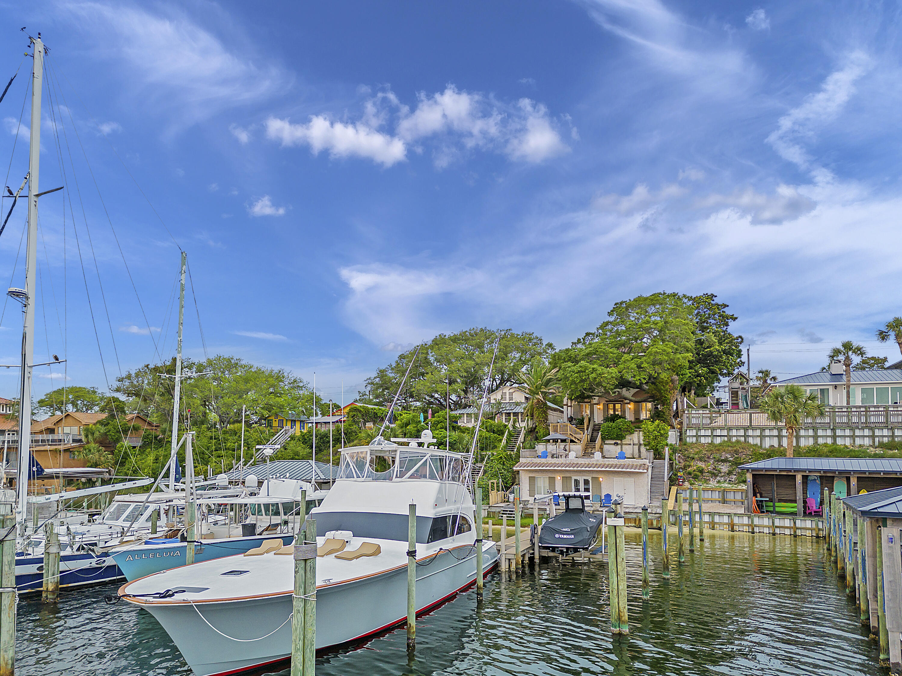 Inspired by the dwellings of the French Riviera and Costa del Sol, this custom built waterfront home on the Destin Harbor was designed for the discerning buyer. The fortified ICF concrete construction is prominently positioned above the Harbor providing beautiful southerly views towards Destin's East Pass. The antique doors on the main level are reminiscent of 16th Century Renaissance architecture of the Tuscan countryside. Complimenting the doors are reclaimed barn wood floors from TN and accompanying wood beams in the ceiling, topped off with a tongue and groove accented ceiling in the living room. Custom designed stair railings, solid wood doors, and various areas of beautiful tile top off some additional architectural features. Flowing outside the main living level is a stunning outdoor living space complete with a 200 year old oak tree (Grace) and a multi-terraced backyard. Soak your cares away in the hot tub as you take in the water views. Working your way down to the dock, you will find a guest house with a vintage vibe, complete with bedroom, bath, and kitchenette. The dock is amply equipped for a variety of vessel mooring, including a 24'x60' slip to accommodate larger boats. The exterior finish of the home is uniquely designed with a locally sourced oyster shell and coquina tabby finish. The main level is rounded off with the addition of a 2 car garage with prominent storage. Upstairs includes the Master Bedroom and Bath with private porch to enjoy the views. You will also find a living room upstairs, 2 additional bedrooms, laundry room, and bonus room (currently being utilized as a 5th bedroom but has no closet in the room). Located in the hear of Destin, this home is just a short stroll to some of the best restaurants on the Emerald Coast, beaches, shopping, and all the activities located at Harborwalk.