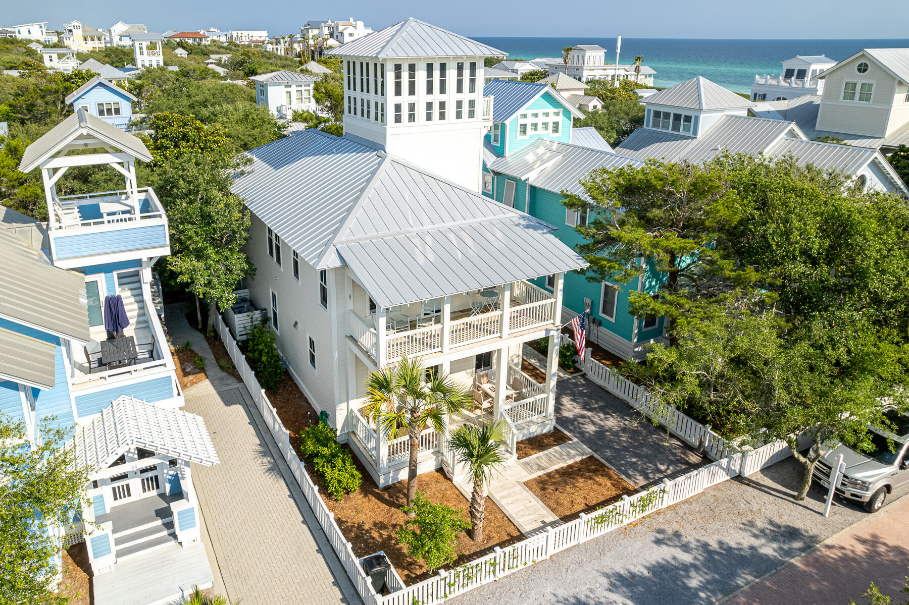 Completed in 2021, the main house is perfectly located four lots in from 30A. The front porch spans the width of the home and expands the living area to converse with neighbors passing by or play your favorite board game. Once inside, an open floor plan is revealed with ten-foot ceilings and crisp white painted wood walls. The custom built upholstered banquette with storage beneath runs the full length of the dining area. The stylish wood dining table with wicker chairs complements the dining area.  The kitchen is the family chef's dream, starting with a 10' quartzite countertop island that seats four comfortably. Custom-made cabinets offer plenty of storage. Commercial line Subzero refrigerator, Wolf 4 burner gas stove with griddle, white farm style sink, LG dishwasher, coffee bar/ appliance cabinet and white subway tile back splash complete the kitchen. A sand room with sink and storage is located by the side entrance of the home, and just beyond is a half bath. The spacious living area includes 2 over-stuffed white slip covered sofas and chairs. A guest bedroom is currently open to the living area, the addition of sliding doors would create privacy for the 4th bedroom. A full bath is also on the first level.  10' ceilings continue on the second level.  Den with twin sofas for extra sleeping separates the primary suite from the guest suites. The black iron king bed with luxurious bed linens creates a cozy retreat.  Access to a private porch directly from the primary suite. The primary bath features double sinks, white subway tile shower, and walk-in closet. Two guest bedrooms, each with private baths and walk-in closets are also on this level.  From the den, halfway up to the tower is a half bath and refrigerator. Continue ascending the stairs to the enclosed tower that extends above the surrounding rooftops, the perfect office, if needed. Step out on to a balcony with panoramic views of the emerald green waters of Gulf of Mexico and extraordinary sunsets. The main house includes a whole house sprinkler system. Rounding out this masterpiece is the separate one bedroom, one bath guest quarters. Built prior to the main house and has been updated. Features include a comfy living area, kitchen, balcony, and washer/dryer. Paved driveway with onsite parking. Excellent location to Seaside town center and amenities.
