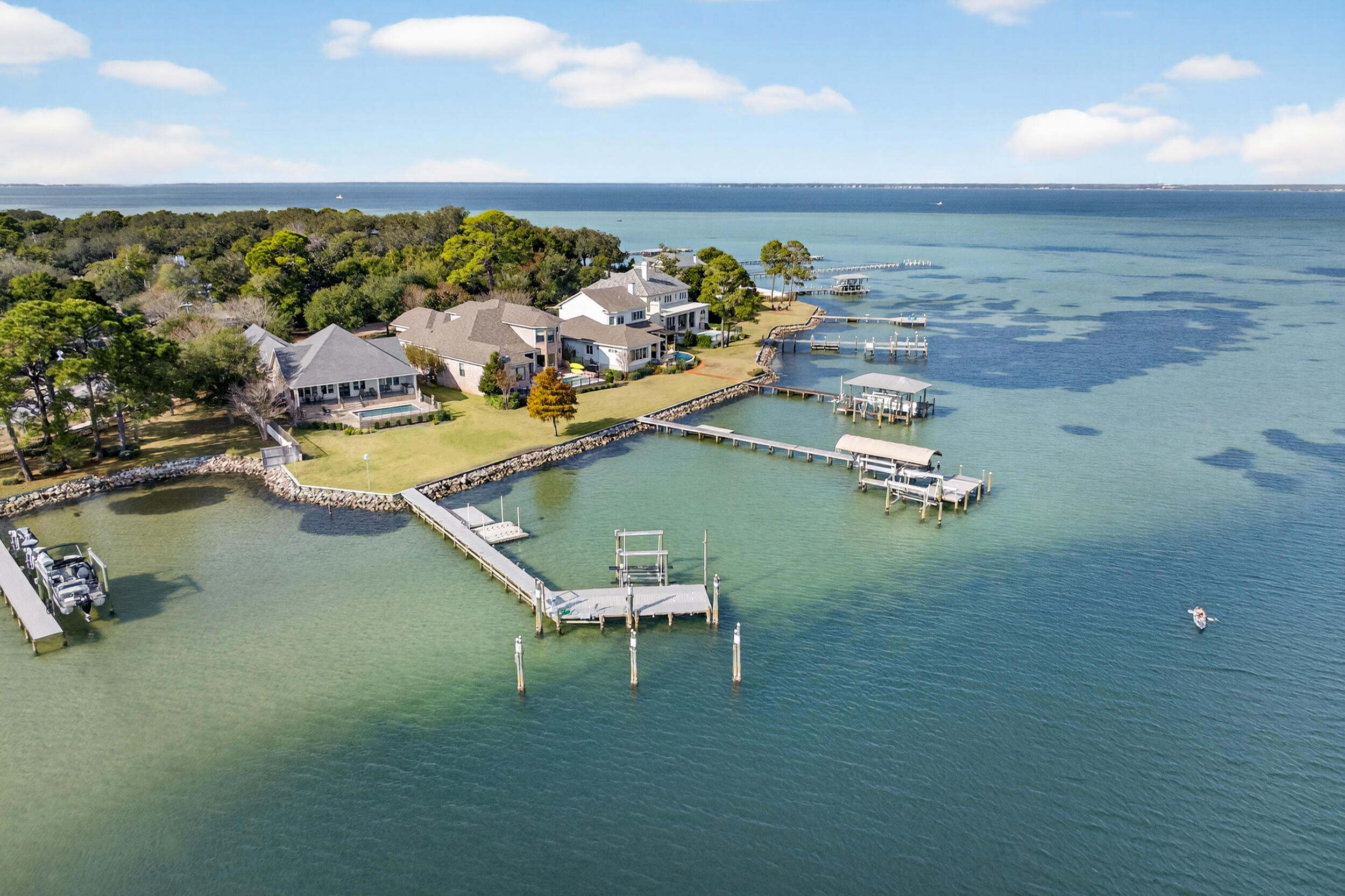 901 Peacock's Point Drive offers a rare single-level waterfront residence positioned at the mouth of Joe's Bayou with direct access to the Choctawhatchee Bay. The home spans approximately 2,776 square feet with four bedrooms and two and a half baths arranged in a practical split floor plan that maximizes privacy and natural light throughout.

The entry flows into an open living area with a wall of windows that frames the water and brings in consistent bay views. Reclaimed wood flooring sourced from an 1890s Chicago train station adds character without overwhelming the clean coastal aesthetic. The kitchen, dining, and living spaces connect easily, creating a central gathering area suited for both everyday living and entertaining. The primary suite sits in its own wing with... unobstructed water views, a spacious bath, and direct access to the outdoor living area. The additional bedrooms are positioned on the opposite side of the home along a private hallway and share a full bath.

Outdoor spaces are designed for functional waterfront living. A covered porch extends the main living area and overlooks the saltwater pool and bay. The property includes a deep water boat slip, an additional slip with lift, and quick access to Destin Harbor and the Gulf. The three car garage provides ample storage for vehicles and coastal gear.

Impact resistant windows, spray foam insulation, a whole-home generator, and other thoughtful construction updates contribute to the home's comfort and efficiency. 901 Peacock's Point Drive offers a refined single level layout on a protected deep water location in one of Destin's most desirable bayside enclaves.
