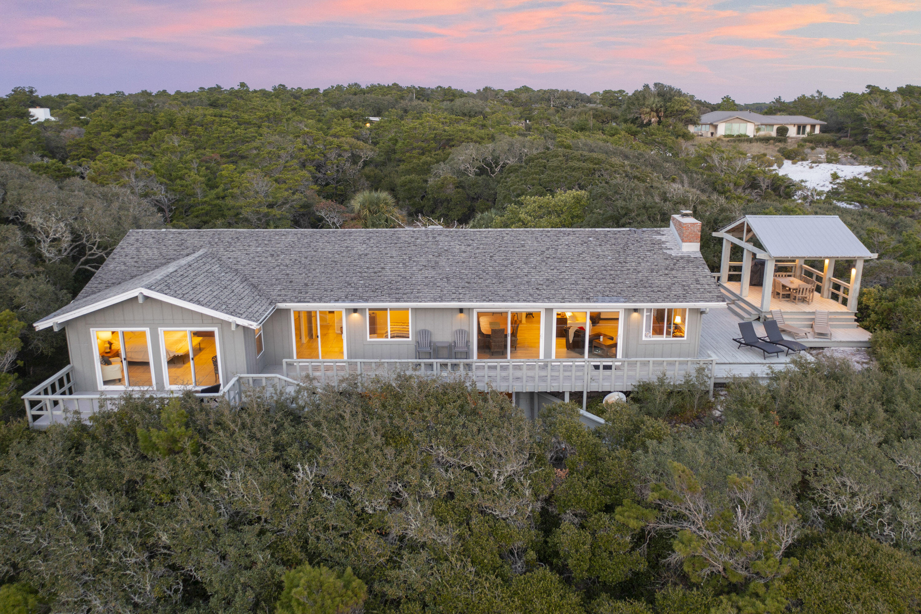 Nestled in the highly coveted Four Mile Village, Mockingbird Lane offers an exceptional opportunity to own a stunning luxury home nestled on an acre lot with panoramic views of the Gulf of Mexico. Perched on a hill and surrounded by lush trees, this private retreat offers the perfect blend of tranquility and natural beauty. The home features expansive living spaces with floor-to-ceiling windows, allowing Gulf views to be enjoyed from nearly every room. With four spacious bedrooms, including a master suite with direct balcony access and sweeping ocean views, this residence is a luxury!  The open-concept living area is ideal for entertaining, with a modern kitchen, formal dining room, and cozy living area with a wood-burning fireplace.

In addition to the main house, the property inc