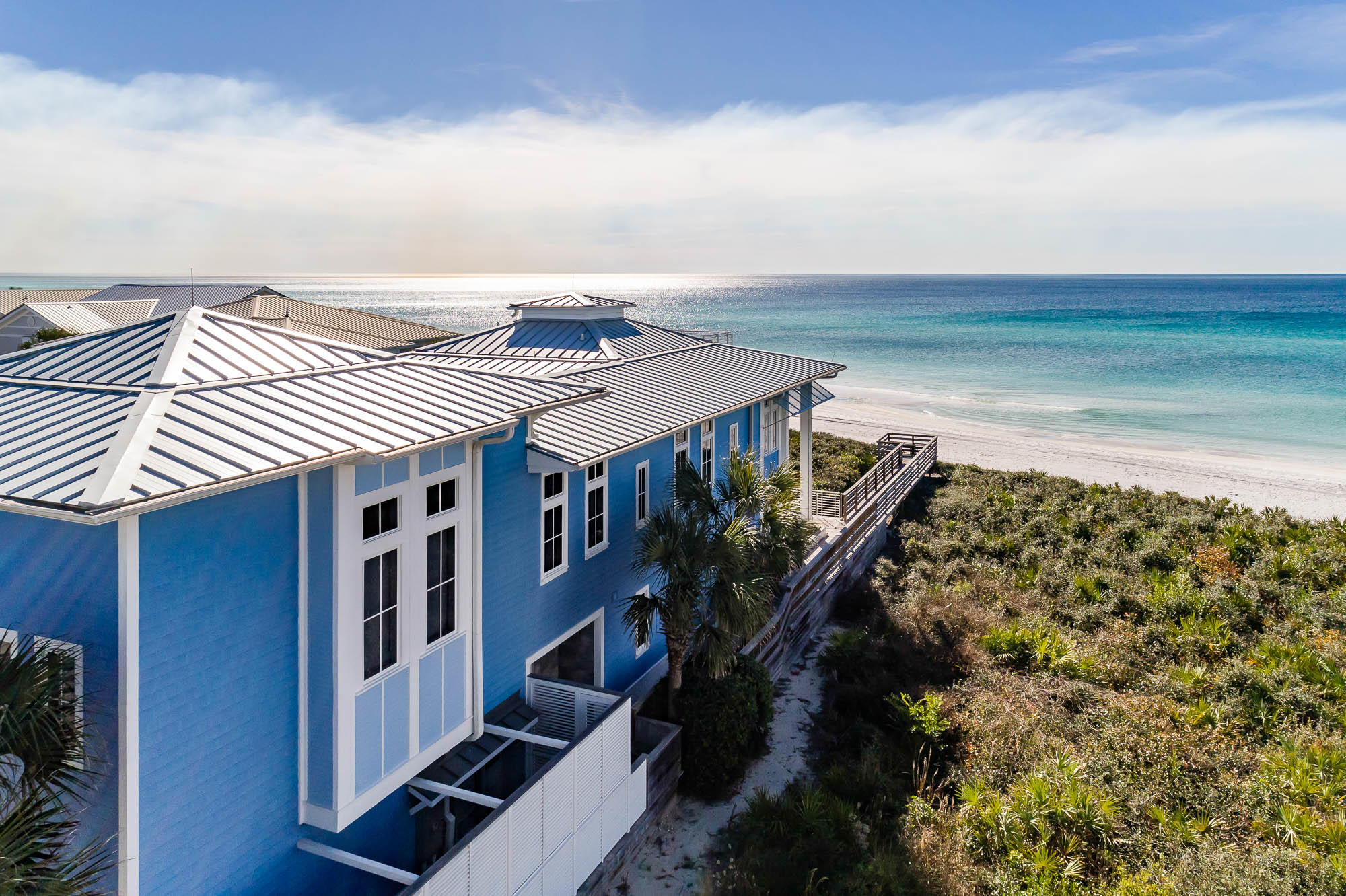 This expansive home nestled in Seagrove Beach offers a beautiful beachfront location with panoramic Gulf views sure to take your breath away. A private courtyard leads you to the entrance of the home. Inside, you're greeted by a light-filled open concept dining and living room complete with panoramic views of the Gulf of Mexico, a gas fireplace and plentiful built-in shelves. The gourmet kitchen boasts coffered ceilings and an impressively large island with seating for eight, two pantries, dual Wolf ovens, dual Wolf warming drawers, an oversized Thermador gas cooktop, and a Sub Zero Refrigerator and Freezer. French doors usher you from the main living area onto the spacious private deck overlooking the beach. A fully equipped wet bar with a wine refrigerator and cooling drawers, an elevator, laundry room, office, dual outdoor showers, and two half bathrooms can also be found on the first floor. A beautiful view overlooking the courtyard greets you as you enter the second floor of the home. An expansive master suite offers breathtaking panoramic Gulf views and an abundance of natural light. The master bathroom features a walk-in shower,  a large jetted Jacuzzi tub, a walk-in closet, an office space and a private balcony overlooking the white, sandy beaches of Seagrove. Three more bedrooms can be found on the second level, each offering private en suite bathrooms, extra storage and stunning views of the Gulf. Located down the hallway is the attached carriage house which also offers a separate entrance from outside. The carriage house atop a 2 car climate controlled garage features a living area that doubles as a theater room, an in-home gym, a sauna and steam shower, as well as a loft overlooking the living space. On the third level, you'll find a wet bar with a refrigerator and additional storage spaces before being drawn out to the incredible roof top deck which offers the perfect place to enjoy breathtaking panoramic views of the Gulf of Mexico and the beach.