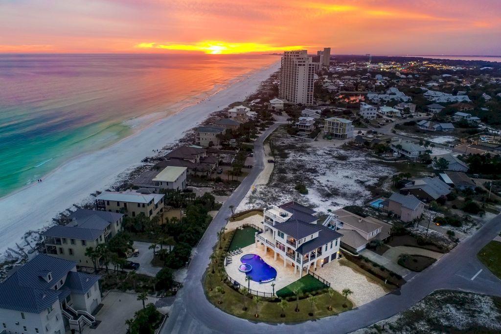 Discover this sleek coastal compound perfectly situated on a sizable 1/3 acre lot directly adjacent to the pristine white sand beaches of the Gulf of Mexico capturing 180 degree gulf views from each of the three finished levels as well as the fourth story rooftop deck. This masterful property is comprised of 5,990 heated and cooled square footage paired with unparalleled indoor and outdoor entertaining space offering several expansive covered porches as well as notable amenities including a private in-home theatre with commercial style outfitting as well as a massive private pool area totaling 1,100 square feet complete with dual fire features, water features and an adjoining spa with ample capacity. This home is an investment magnate with a range of $300,000 - $350,000 in gross projected annual rental income. This is the ultimate beach home masterfully configured to provide unparalleled amenities and designer decor, curated for entertaining with notable features including ample parking, multiple garage storage bays, elevator access to each level and an inverted floor plan which elevates the primary living areas to enjoy expansive gulf views.

The exemplary open floor plan is characterized by optimal living space on each vertical level featuring a private living area accessible by surrounding bedroom suites. The first floor offers a spacious game room and private in-home movie theatre seamlessly flowing to the outdoor living and subsequent private resort style pool area as well as an adjoining spa and covered outdoor summer kitchen & living area complete with putt-putt golf and low maintenance synthetic turf. Other notable features include a private commercial grade elevator, dual master suites with gulf views and adjoining spa like bathrooms with floor to ceiling Calcutta marble tile and built-in pinterest style bunkbeds.

The first floor layout boasts a spacious bunk room complete with an ensuite bath as well as a central living room and adjoining game room with pool table complete with a gaming area and movie theatre. The second floor is the focal point of indoor living space with a spacious living room framed with floor to ceiling windows to soak in the beautiful gulf views, gas fireplace, lounge/entertainment area and open to the massive dining room overlooking the rear amenities and eastern gulf views. The ample sized kitchen features floor-to-ceiling custom cabinetry, stainless refrigerator/freezer, Wolf professional series gas range and double oven, dual dishwashers and side entry pantry anchored by a large center island with gorgeous marble countertops. The second floor also features bedroom suites as well as access to the second story outdoor living area overlooking the lagoon style pool. The third floor features 3 full bedrooms including dual master suites, spacious living room and ample wrap around porches to take in panoramic views. The rooftop deck is the ultimate viewing experience allowing for endless sunsets and 360 views of the emerald green waters of the Gulf.

Gulf pines is an exceptional private neighborhood nestled south of highway 98 perfectly located along the Gulf of Mexico in Miramar Beach, adjacent to the Sandestin Resort. Gulf Pines is a relatively low density neighborhood and the beach is rarely crowded. Gulf Pines has a sizable gulf front pavilion with seating and tables on almost 100 feet of beach for your pleasure and comfort. Golf cart transportation is permitted in this low density neighborhood to conveniently park at the beach. Also, there is a beautiful lake within Gulf Pines, which is perfect for fishing.