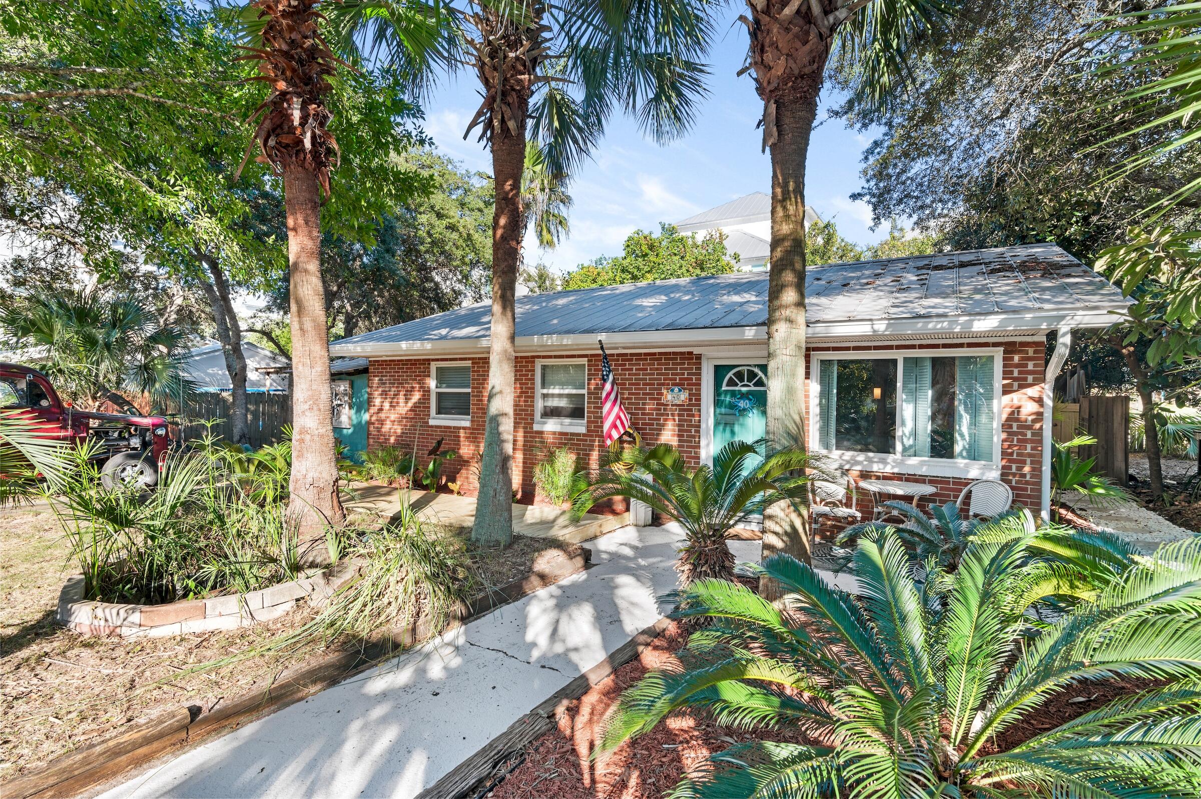 Fantastic one-of-a-kind Florida beach cottage located in the heart of Blue Mountain Beach in desirable Blue Gulf Resort, just a 1/2 mile to the beach & emerald green waters of the Gulf of Mexico! Brand new 'sea salt' paint throughout for a fresh coastal look. The newly added shiplap & wainscoting is a perfect craftsman touch. This home is located in the historic community of the ''Brickyard'' and features an EXTRA HALF LOT, which is rare. This ideal property is a one-level home with ample outdoor living & a prime location just off of 30A. Incredible outdoor space complete with a unique custom areas like a screened-in 'she shed' with metal roof, plentiful sitting areas, outdoor shower & bathroom, Tiki bar, playhouse, multiple sheds & even a jetted tub to unwind in after a day at the beach! Backyard is fenced with 2 side entrances with new wooden gates.
The backyard is also fenced for privacy and can be accessed from the kitchen as well. This brick home has withstood the test of time with good bones and an updated metal roof, new gutters, new French drain added, and new wooden walkway at the front and side. Tropical landscaping surrounds the home lending a nice coastal feel and there is plenty of parking or room for a carport or additional decks, if desired. With the extra half lot, there is room to expand the home too, if desired, for more living space. Interior features tile floors throughout for easy maintenance for beach living. The living area has nice natural light with the large window at the entrance and there is updated lighting throughout and crown molding. Kitchen has an added island great for casual dining with a unique epoxy countertop reminiscent of the ocean. Cabinets were just painted white which aligns with the new shiplap & wainscoting. Kitchen also features stainless steel appliances (brand new fridge 2025) that convey, a custom metal backsplash and a charming dining nook by the large window allowing for good natural light. Original ceilings & wood paneling add to the "Old Florida" charm.

The primary bedroom has enough room for a king bed and features an ensuite half bath with partially tiled walls, wood accent wall and a pedestal sink. There is a shared full bathroom with tiled shower and custom epoxy vanity and updated lighting. There are two guest bedrooms each with crown molding. Head to the backyard off the kitchen and enjoy plentiful areas to unwind and relax in. Back porch is covered with a metal roof along with the amazing screened-in "she shed," the perfect spot to relax and snuggle up with a good book. The extra half lot allows for fantastic outdoor living and entices you to take more time for outside enjoyment and that beach lifestyle everyone desires. The charm of the unique outdoor nooks truly cannot be replicated! This will make a great full time residence or second home as the community is laid back with no HOA fees. There is also great potential as a rental property as similar properties in the area have done as high as $100k in annual income! The vicinity to the beach and exceptional dining & entertainment options nearby makes this a prime investment and one of the best values for 30A overall.

Blue Gulf Resort is a prime location in Blue Mountain close to many conveniences - bike path, For the Health of It market, Blue Mountian Bakery, Big Daddy's Bike Shop, McTighes, Cowgirl Kitchen, Mimmo's, Real + Raw, Gulf Place, and even Grayton Beach State Park in close vicinity. Access the beach just over 1/2 a mile away. The nearest public access is at the south end of Highway 83 with parking and restrooms but there is also an additional access across the street behind Redfish Circle that this community has an easement to access.

Blue Mountain Beach is the highest elevation of Florida's Gulf Coast lending incredible views and beautiful natural dunes and wild flowers. Enjoy the great outdoors with the surrounding state parks, nature trials and the 22-mile bike & jogging path. Kayak or paddle board on one of the rare coastal dune lakes and experience a unique ecosystem that is only available to approximately 11 locations in the world! You are also close to the picturesque towns of Seaside, WaterColor and Rosemary Beach. Do not miss out on this incredible opportunity to own a historic updated 3-bedroom home in a prime location close the beach!