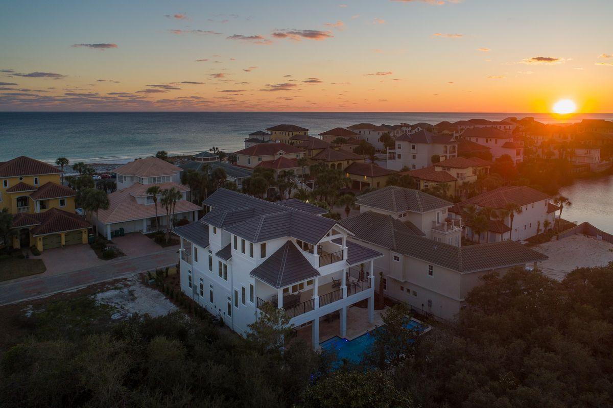 Newly built and primely positioned, this exemplary coastal retreat is perfectly situated to capture gulf views & masterfully configured providing unparalleled amenities including a watermark-built private resort style pool area complete with a sunken swim-up bar as well as an adjoining spa, in-pool concrete picnic table & covered outdoor summer kitchen. Located second tier in the exclusive gated neighborhood of Destiny, this newly built custom home was thoughtfully designed to provide exceptional gulf views and maximize functionality with finely appointed coastal contemporary finishes while affording optimal comfort & living space. Notable features include multiple indoor and outdoor living areas, private commercial grade elevator, dual master suites with gulf views, built-in bunk beds, multiple living areas as well as expansive private porches on both the north and south sides of the home soaking in Gulf and lake views. The first floor layout boasts a spacious living room, full size laundry area, two large bedroom suites with ensuite bathrooms as well as an industrial style game room complete with stocked built in wet bar and offering immediate access to the private pool area. The rear yard is enclosed by fenced privacy and is maturely landscaped offering a massive pool and adjoining spa with ample room to entertain as well as yielding a full pool bathroom & outdoor shower with easy access to the beach. The second floor is the focal point of indoor living space with a coastalized living room featuring pecky cypress ceilings and walls, floor to ceiling windows to soak in natural light & gulf views and open to the sizable chef's kitchen & dining room for optimal flow. The ample sized kitchen features floor-to-ceiling custom cabinetry, Thermador appliances and professional series gas range, ample storage and is anchored by a massive center island crowned with gorgeous quartz countertops. The second floor also features two full bedrooms with a full bathroom as well as access to the second story outdoor dining area overlooking the resort style pool. The third floor features two full bedrooms including dual master suites with spacious porches, private laundry area as well as a south facing viewing deck to maximize the incredible gulf views that surround this prestigious home. Destiny owners enjoy a 3,000' beach access point steps from the home as well as a full clubhouse, gated security, fitness center, tennis courts and is centrally located near Destin's world class golfing, dining, restaurants & entertainment.