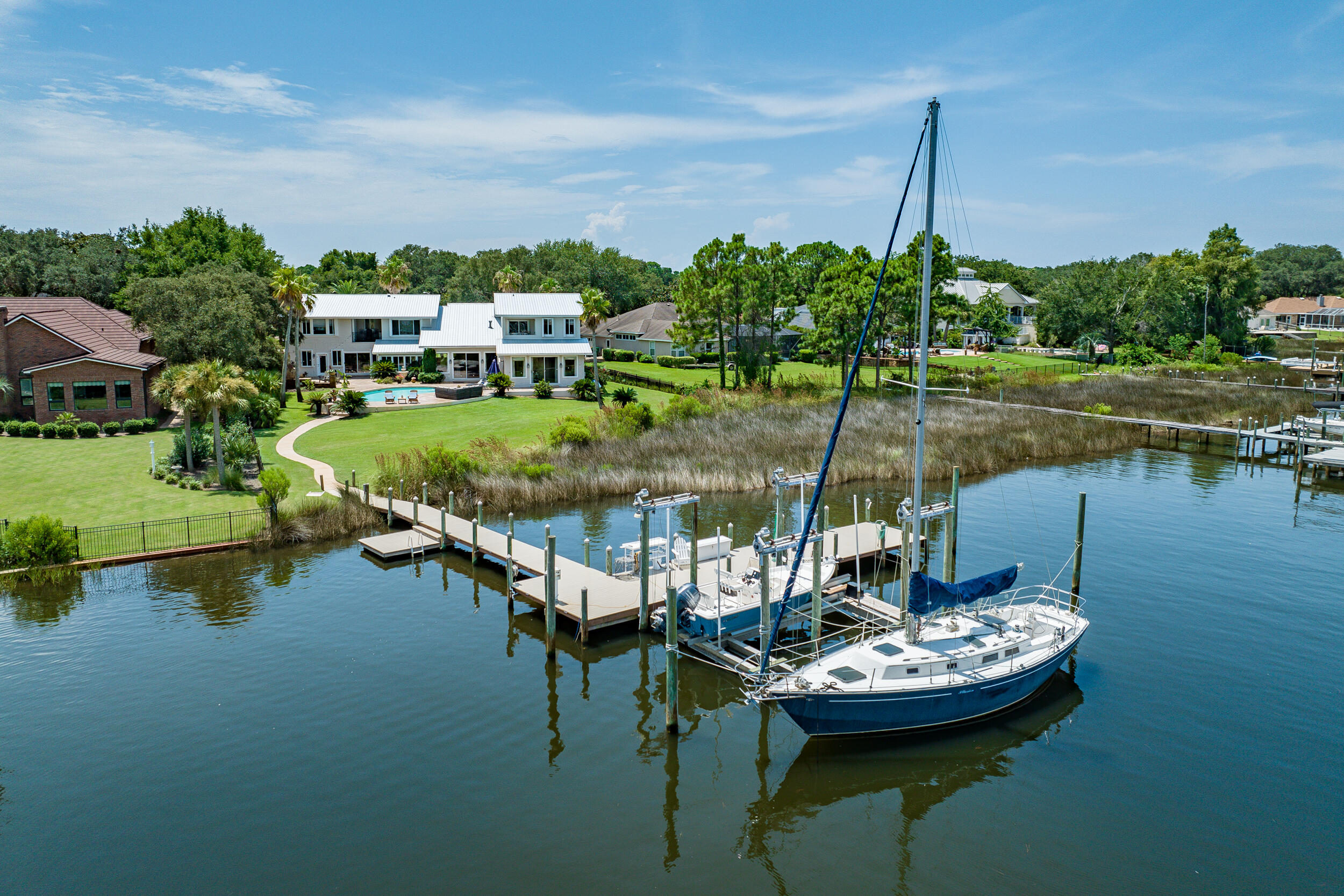 $100,000 price reduction.  Fabulous Deepwater, Bayou front Estate with incredible Bay & Bayou views with 150' of waterfront.  Home boasts of 5509 SF with multiple living areas, 5 spacious ensuite bedrooms, (4 bedrooms with bay views) 2+ in home offices, gym area, 2 laundries, 2 Mother-in-law Suites., 2 Bay balconies, 3 kitchens & more. The Dock has been upgraded with Trex decking & can accommodate multiple boats and other watercraft.  Large Dock includes a 30,000-pound, 4 motor boatlift. Outdoor gas kitchen with wood burning fireplace compliment the pool and wonderful views. New metal roof, exterior paint and exterior lighting, in 2023. The Gourmet kitchen has a beautiful granite island, stainless appliances, 6 burner Wolf Gas Range, high-end cabinetry and eat in kitchen. 3 HVAC Systems. Home has partial Hurricane Shutters, 2 new instant water heaters, new sod, and new pool pump.  It also conveys with a central vacuum system, gas fireplace in Living room and Primary, and interior finished attic.  Recent upgrades have been completed to primary bath and mother-in-law kitchen and bath.  Master bath has 3 vanities.  The ceiling heights in the living room are up to 17', the east wing mother-in-las ceiling heights are 12' and west wing mother-in-law suite has up to 12' ceiling heights.    The long driveway can accommodate 8+ vehicles for your family and guests.  The garage is oversized with shelving installed.   Olympus Home insurance policy is $7854.00 per year.  Frontline Flood Policy is $827 per year.  Flood Zone is AE.