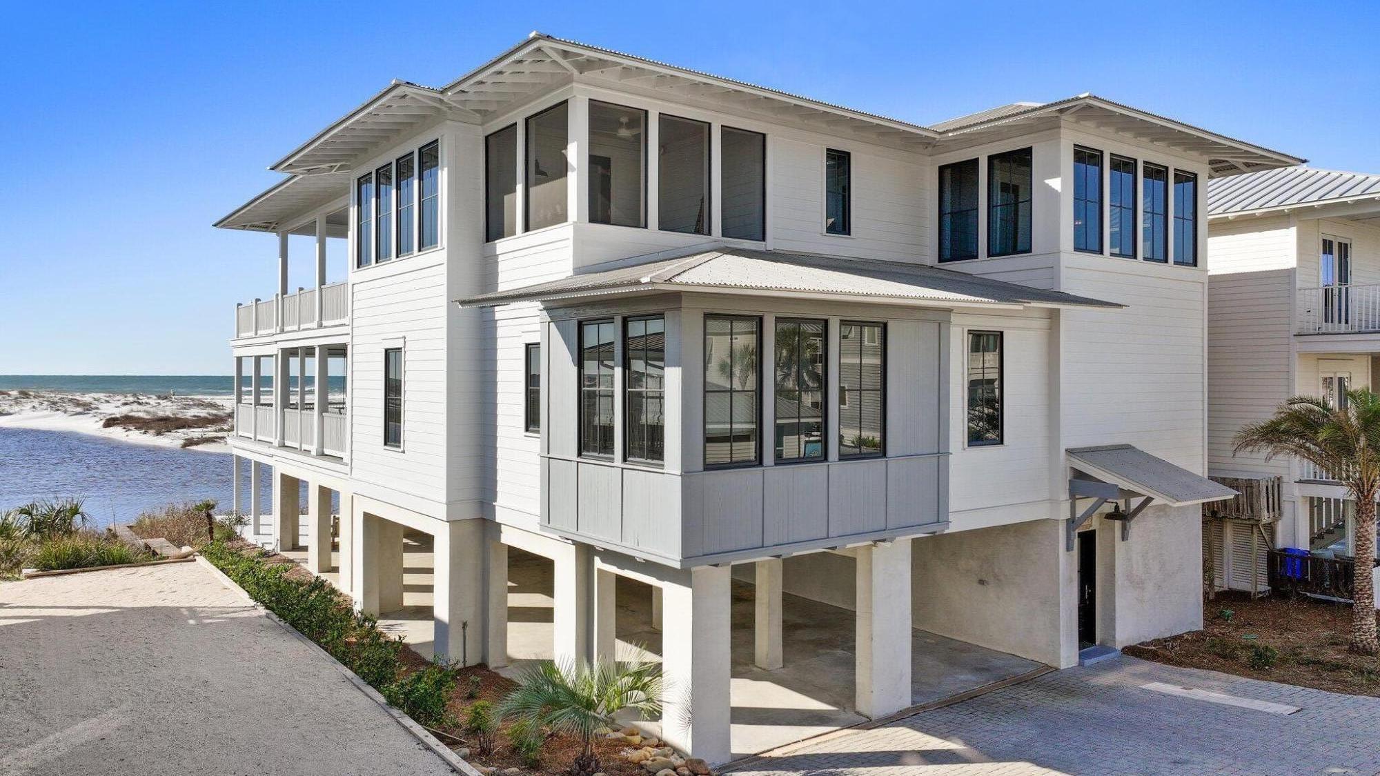 A symphony of elegance in Grayton Beach, Lollygag commands the most coveted location on 30A, where Western Lake meets the Gulf of America in an awe-inspiring convergence of coastal beauty. Positioned at the curve of the Grayton Beach outfall, this home offers a rare and uninterrupted panorama, with forever-protected views of the dune lake, sugar-white sands, and emerald Gulf waters. Its setting is as private as it is breathtaking.
Designed with an emphasis on both luxury and resilience, Lollygag is a fortress of coastal design, featuring a bedrock-anchored seawall ensuring lasting protection without compromising the natural beauty that surrounds it. Inside, every element has been thoughtfully curated to create a home that is both extraordinary in design and effortless in function. A commercial-grade elevator provides seamless access across all three levels, while wide hallways enhance flow and accessibility.
The first floor is dedicated to comfort and convenience, featuring a steam room (sauna), full laundry, and half bath. The second level hosts two king suites, a queen suite, and a six-bed bunk room, each, except bunkroom, has its own private covered porch to take in the endless views. A handicap-accessible bath serves the bunk room, ensuring comfort for every guest. A swing bed on the second-floor porch provides a tranquil retreat, perfect for soaking in the coastal serenity.
The third floor is where Lollygag truly shines. A grand great room, private office, screened-in porch, and an expansive seaward-facing deck with another swing bed create the ultimate indoor-outdoor living experience. Whether gathering in the open concept living space or unwinding as the sun dips below the horizon, every moment in this home is framed by the natural beauty of 30A's most remarkable setting.
From its high-end appliances and integrated surround sound to its durable metal roof, hardboard siding, and Trex decking, every element of Lollygag speaks to quality and craftsmanship. Under-home covered parking with custom lighting enhances convenience, while two full outdoor showers offer the perfect way to refresh after a day on the water.
With an unrivaled location, timeless design, and a level of craftsmanship rarely found, Lollygag stands as a benchmark of luxury along 30A. Used as a second home and not a rental, its pristine condition and exclusivity remain intact. Private showings by appointment only.