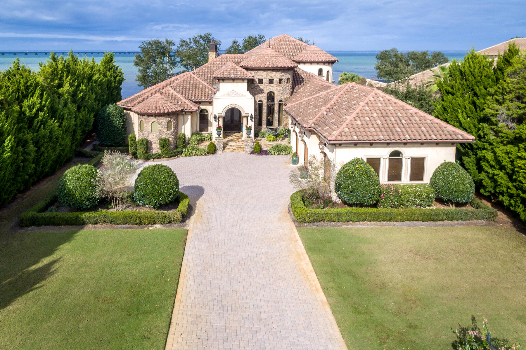 Currently under contract with contingencies. Seller still accepting back up offers during inspection period.
ICF-constructed architectural beauty unites the distinctive details of a stately chateau-style home with modern, coastal themes for an awe-inspiring waterfront experience. Situated on 118 feet of desirable shoreline, this estate features an abundance of alfresco living including an almost 1200-sq-ft screened-in lanai with heated, saltwater pool, spa, summer kitchen, and outdoor fireplace and a newly constructed dock. Recently updated by Lovelace Interiors, every detail in this home has been carefully considered. This showpiece's luxurious appointments, alluring detailing, and opulent landscaping are matched in exquisiteness only by the surrounding natural scenery. Old World architectural elements like stone and stucco exterior, a grand entry, sweeping arches, polished marble floors, interior columns, aged-finish walls, spiral staircase, and raised ceilings are timeless and elegant. Ceilings are specially beautified with wood beams, pecky cypress, glamorous chandeliers, double tray ceilings, or a hand painted mural. Custom built-ins, handcrafted doors, beveled glass, 21' and 12' ceilings, ornamental stone fireplaces, and semi-circled walls give an inimitable elegance to the design scheme of this home. Views of sparkling bay waters flow artfully throughout the interior. The chef's kitchen is exceptionally tasteful with custom cabinetry, granite counters, and stone sink. It is uniquely spacious, accommodating large gatherings of guests, and flows easily into the three dining areas. Kitchen amenities include: Viking appliances, two Bosch dishwashers, large walk-in pantry, butler's area, and wine room. In the adjacent family room, an expanse of disappearing glass doors seamlessly merge the interior with the lanai. The master suite is luxuriously appointed and generously sized. Double wood doors lead directly to the lanai and pool. The master bath features 2 beautiful Carrera marble statues, a large walk-in shower, jetted tub, and boutique-style closet. A 2nd story bonus room and adjoining bayfront balcony are substantially sized to accommodate additional entertaining space. Recent improvements include a new dock with electricity and water, 1-year-old pool heater, new lighting, 1-year-old HVAC, and new irrigation system. Additionally, this home offers a 3-car garage, home office with custom cabinetry, and whole house generator. Select furnishings remain with an acceptable offer.  Regatta Bay is an exclusive, gated golf community with an acclaimed 6,894-yard golf course, golf club with dining, and 2 tennis courts.