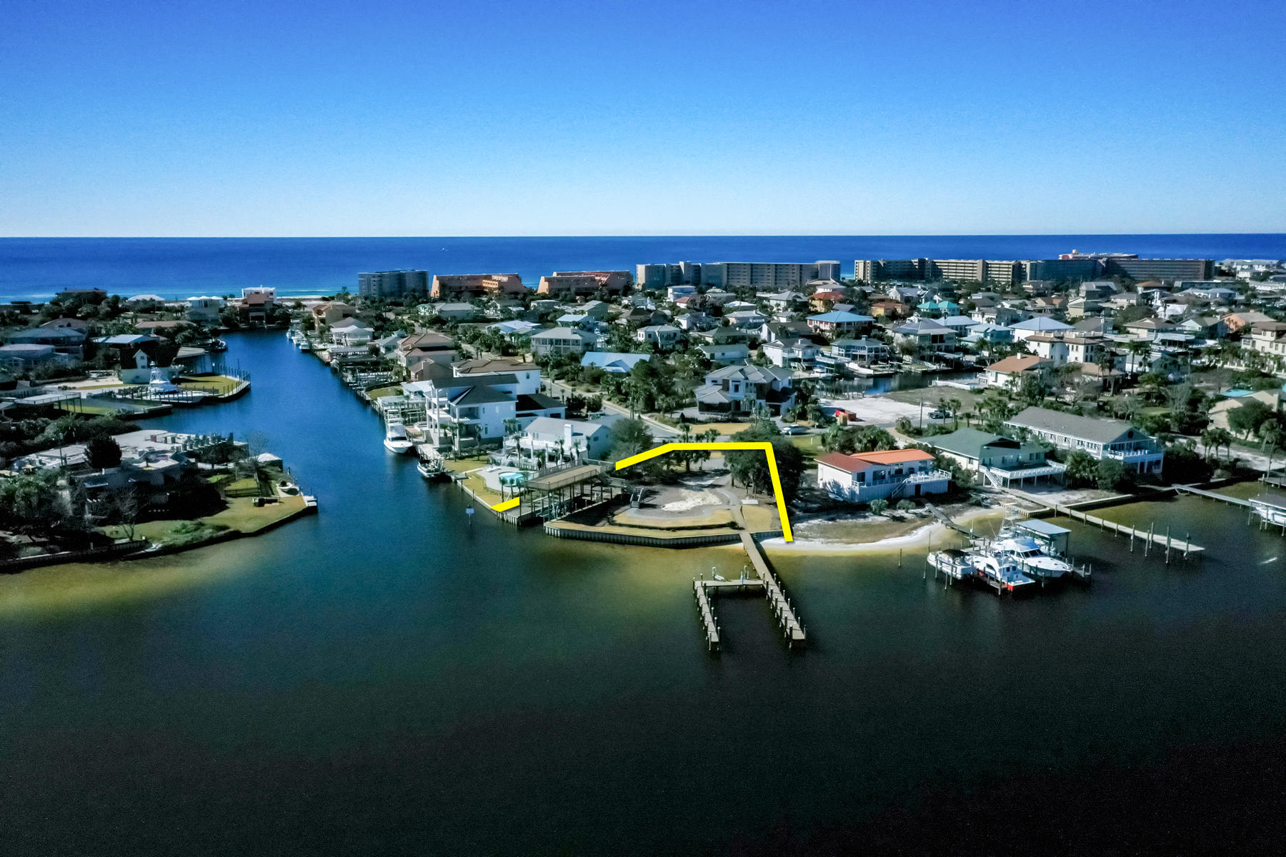 One of the most remarkable deep-water lots in all of Destin, Florida, which is beautifully oriented on the exclusive address of Holiday Isle and surrounded by 160'+ of the scenic harbor.  This lot offers a nearly pad-site ready opportunity to custom design and build your coastal retreat.  The elevation of the site is superb, and the vinyl sheet-pile bulkhead and terracing that are already in place will save the buyer considerable site costs.  A few stairs down from one of the piers give access to your private beach.  The property consists of two existing docks, which is incredibly rare, one of which will accommodate three lengthy vessels, and the other single-slip dock offers overhead cover, which cover also functions also as an expansive 18' x 50' sun deck.  Please.. ...note the uploaded schematic of the docks that reveal relevant measurements. Please inquire for further details, and to schedule your private showing.