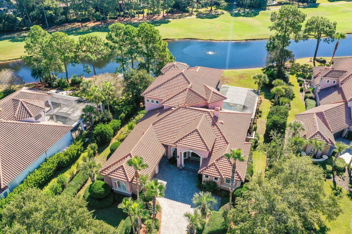 This palatial home in Burnt Pine delivers endless living space overlooking peaceful lake and golf course vistas. The private outlook enjoyed from the pool terrace, living areas, and master bedroom includes 117 feet of lake frontage. A paved driveway leads to a three-car garage. Step through the entrance door and appreciate the impressive sitting area with views of the lush outdoor living area and tropical landscaping. Cool tile floors, grand pillars and elaborate tray ceilings set the scene for a home designed for comfort and luxury. There's a handy granite-topped wet bar with drink refrigerator for serving perfectly chilled drinks to welcome guests. Views from the living area, breakfast nook and kitchen overlook the pool, providing seamless indoor-outdoor living with two fully retractable NanaWalls. The capacious screened lanai incorporates a lagoon pool with hot tub. Warmed by heaters and the stone-clad outdoor fireplace, the covered terrace is the perfect setting for entertaining or watching visiting herons and wildlife. It includes a covered outdoor kitchen with a grill and island bar. Views extend across the stunning lagoon pool and hot tub to the lush golf course beyond. The ground-floor master has everything you could wish for: two closets with built-ins, a huge wet-room-style shower with wall jets, a whirlpool garden tub, and direct access to the pool. The chef's kitchen is equally well appointed with double oven, granite breakfast bar, separate wine cellar, butler pantry, and huge laundry room. Enjoy lake and golf course views from the generous ground floor study with built-ins.  The guest bedroom suite on the ground floor offers privacy. Upstairs, there's a game/media room, kitchenette and three further guest suites. The screened balcony on the second floor offers stunning golf and lake views to start the day. Burnt Pine is a gated upscale community within the outstanding Sandestin Golf and Beach Resort. Residents have access to four championship golf courses, tennis, the beach, a marina, entertainment, shopping and upscale dining. It's all part of the Burnt Pine lifestyle.