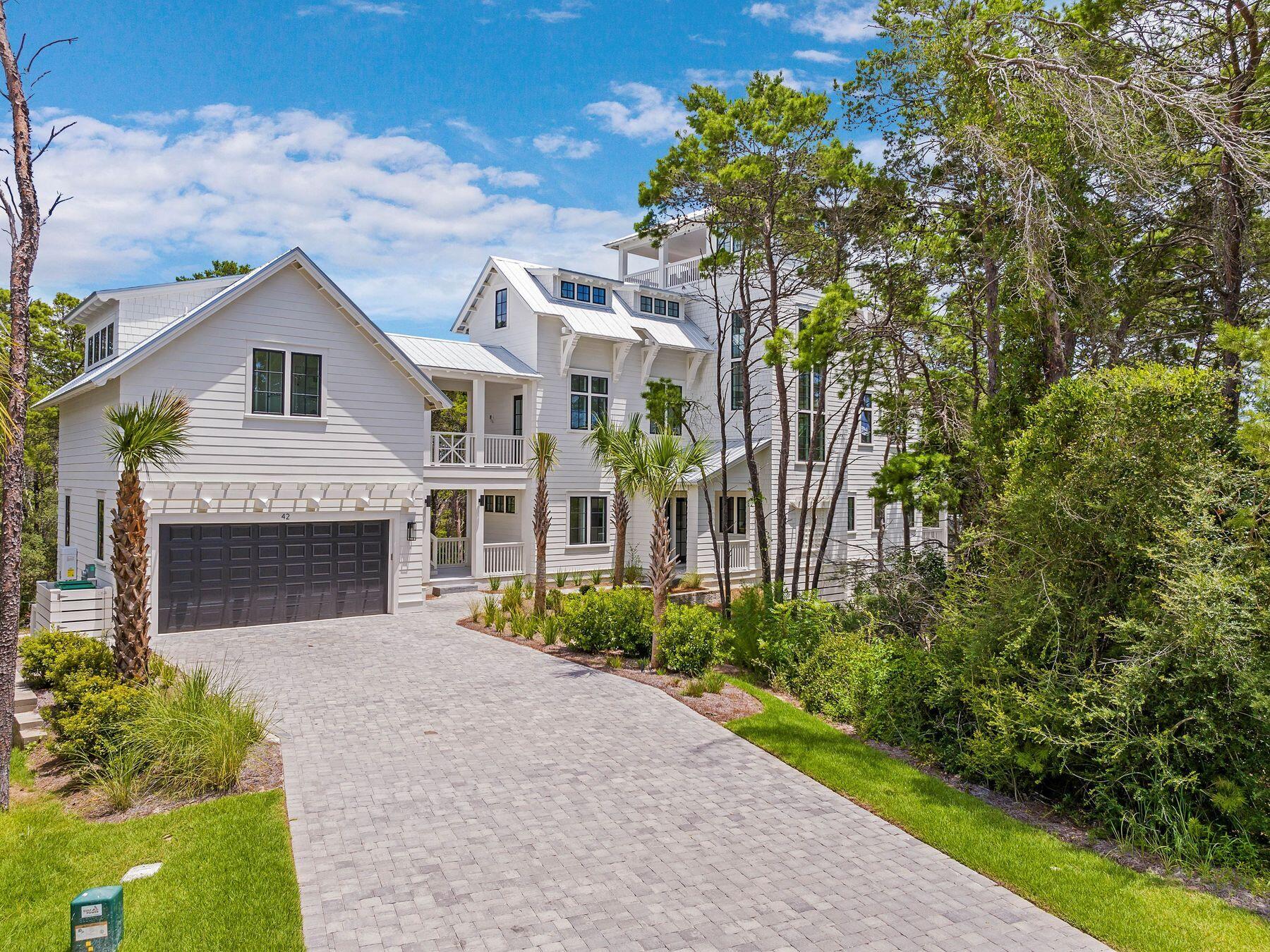 Offering captivating gulf views, plentiful outdoor entertainment areas, and a sizable interior, this four-story home on Grande Point Circle provides community living on an oversized state park-adjacent lot. Designed by Katie Milner of Coastal Architects and custom built by Dave Hogan of 30A Builders, this three-story plus rooftop home provides more than 4,150 square feet of interior space, spread across five bedrooms and multiple living areas, as well as an attached carriage house with a studio and private balcony overlooking Camp Helen State Park. The home's main level features a spacious foyer with a sitting area, two guest suites and a bunk room. Understairs storage is available for additional convenience, as is the three-stop elevator. The bedrooms feature fully finished closets with custom built-in drawers, as well as Carrara tile showers, quartz countertops and custom lighting fixtures for a clean, modern take on a coastal home. The stairwell to the second and third floors are flooded with natural light thanks to oversized windows adorning the space, while white oak flooring and crisply painted balusters bridge the gap between traditional craftsman and modern styling.  The second level of the home features an open living and kitchen area complete with an oversized center island, Fisher & Paykel appliances including an induction range, custom cabinets with ample storage and large transom windows to connect the surroundings to the home. The living area featured shiplap walls, a remote-start fireplace, and French doors leading to the southern-facing covered balcony with grilling space. Next to the living space, a separate dining area with breathtaking state park views provides a refined area for spending time with friends and family. Down the second-story hallway, a beautifully designed laundry space with shelving and storage is provided, as well as a half bath and a bedroom space, currently used as a home office. Outside, the doors of the hallway open to the breezeway with an outdoor living area, effortlessly connecting the carriage house to the home, as well as a stairway to the two-car garage featuring an epoxy floor. The third story is the primary suite, offering a freestanding soaking tub, a double vanity with designer finishes, a glass walk-in shower, an expansive walk-in closet with two separate storage areas and a primary bedroom with a private covered balcony. Above the primary suite is the expansive rooftop deck with plenty of open area for relaxation and fun, while a covered dining space enhances alfresco experiences alongside the full summer kitchen, all while gifting direct views of the Gulf of Mexico.