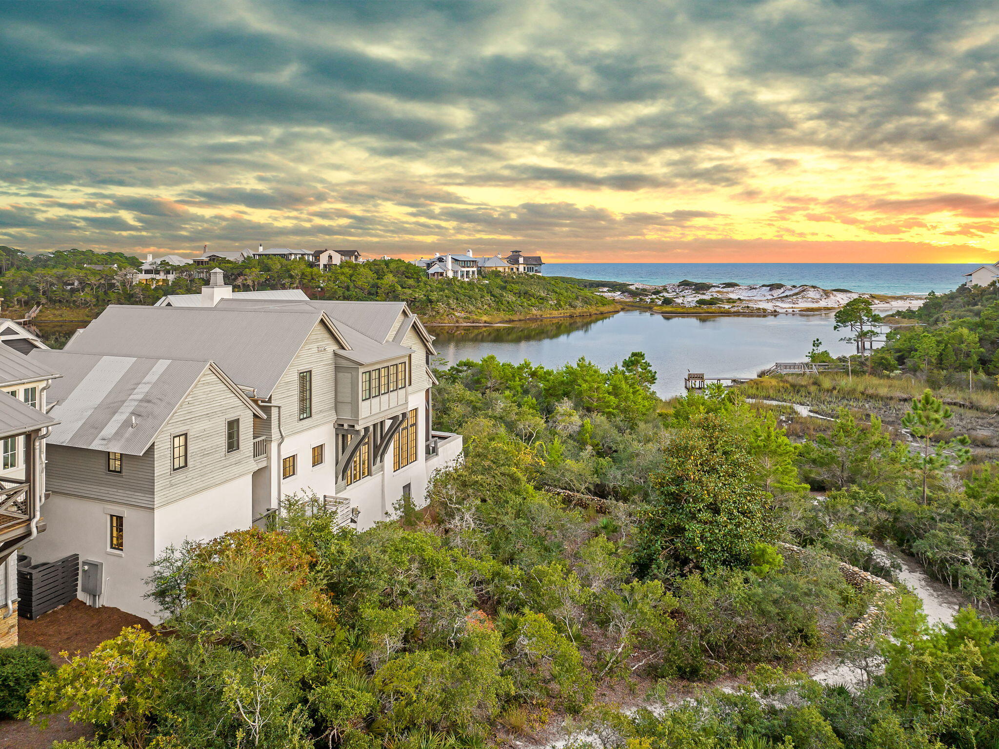 Suspended between the Gulf and Draper Lake offering sweeping panoramic views, 28 Bluff Lane stands as a study in coastal elegance with an exemplary waterfront lifestyle.

Designed by Domin Bock Architects and set within the gated Draper Lake Coastal Village, this lakefront estate embodies ambient luxury through architectural precision and an effortless connection to its surroundings. With panoramic views that capture both Draper Lake and the Gulf of Mexico, the residence delivers a rare duality: the calm of the lake and the energy of the open sea. The main level unveils 12-foot exposed-beam ceilings, white oak floors, and an open concept anchored by a chef's kitchen appointed with Wolf and Sub-Zero appliances. A discreet wet bar and sculpted millwork elevate the experience, while four sets of French doors blur the threshold between interior and exterior living. Beyond them, an infinity-edge pool appears to flow seamlessly into the lake below.

Upstairs, the primary suite commands cinematic views from a private terrace and features dual closets and a spa-like bath. Two guest bedrooms and a media lounge complete the upper level, while a carriage house suite above the garage provides refined privacy for guests.

Within Draper Lake Coastal Village, residents enjoy access to community pools, scenic trails, and an observation tower, all within a rental-restricted community designed for enduring privacy. Just moments from the best of 30A, 28 Bluff Lane is more than a residence; it is a modern coastal composition where architecture, landscape, and lifestyle align.