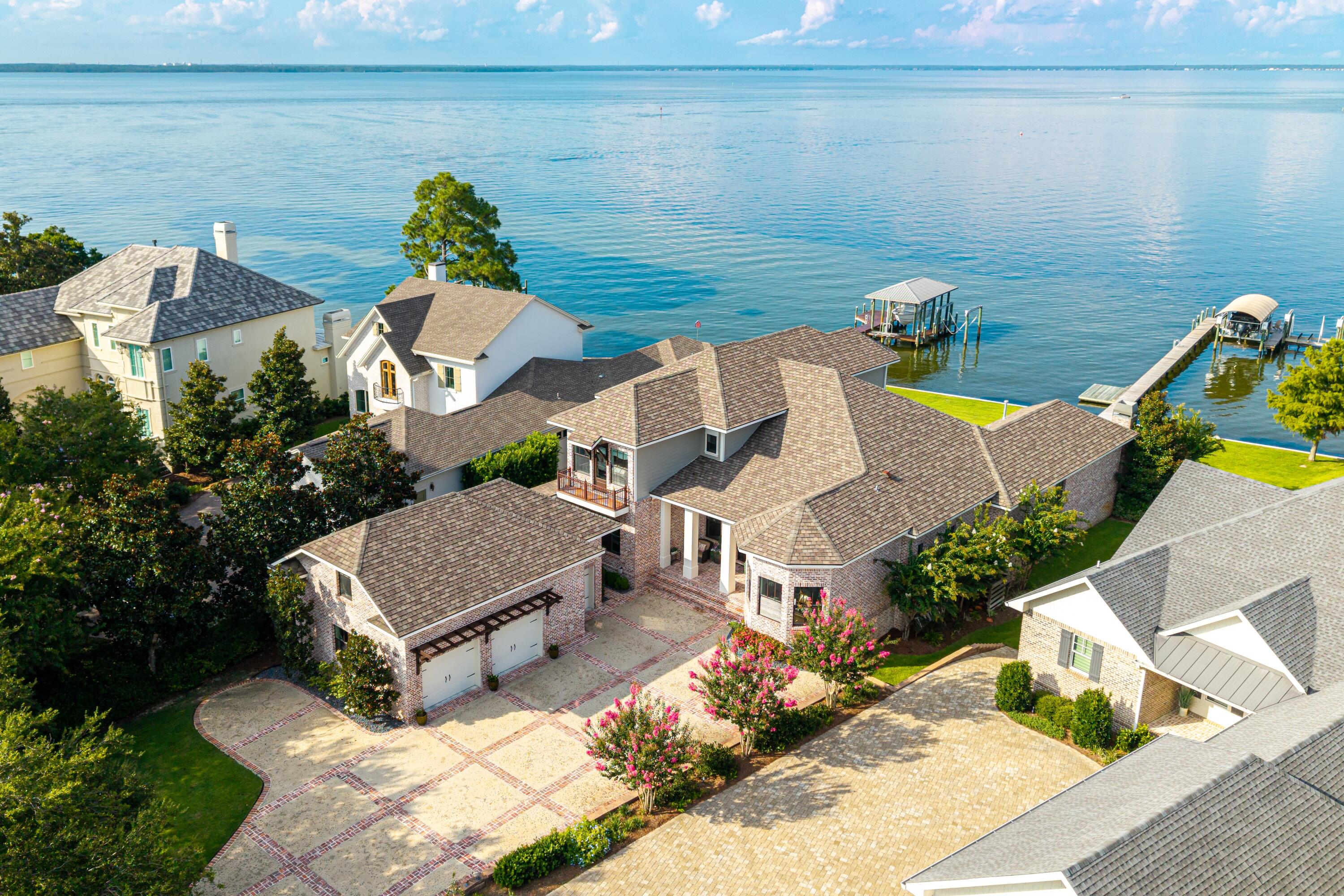 Nestled along the sparkling waters of the Choctawhatchee Bay in one of Destin's most sought-after gated communities, this custom-built 5-bedroom, 6-bath residence blends timeless craftsmanship with relaxed coastal living. Reclaimed brick, inside and out, sets the tone for a home that feels both elegant and welcoming. Inside, a thoughtful open floor plan invites gathering and connection, with soaring ceilings, a formal dining room, sunny breakfast nook, and a great room designed for easy entertaining. The chef's kitchen is a true centerpiece, featuring premium Thermador appliances, a wine fridge, a generous island, and an entertainer's dream rear butler's pantry with an extra refrigerator. The waterfront primary suite is a private retreat, complete with a cozy fireplace and spa-like bath. Pamper yourself with a steam shower, garden tub and a large custom walk-in closet.
Outdoors, the magic continues. A saltwater pool with tanning ledge and hot tub overlooks the bay, while the private dockwith two boat liftsmakes adventures on the water effortless. An expansive covered outdoor kitchen is outfitted with a Coyote grill and refrigerator. An outdoor wood-burning fireplace, plus an additional open-air kitchen area with a Big Green Egg is meant for memorable cookouts.
A heated and cooled bonus room over the two-car garage becomes the ultimate game space, perfect for lively nights or laid-back afternoons.
With no detail overlookedcustom speakers throughout, a security system, and multiple porches for soaking in the viewsthis bayfront home offers the best of coastal living in a setting you'll never want to leave.