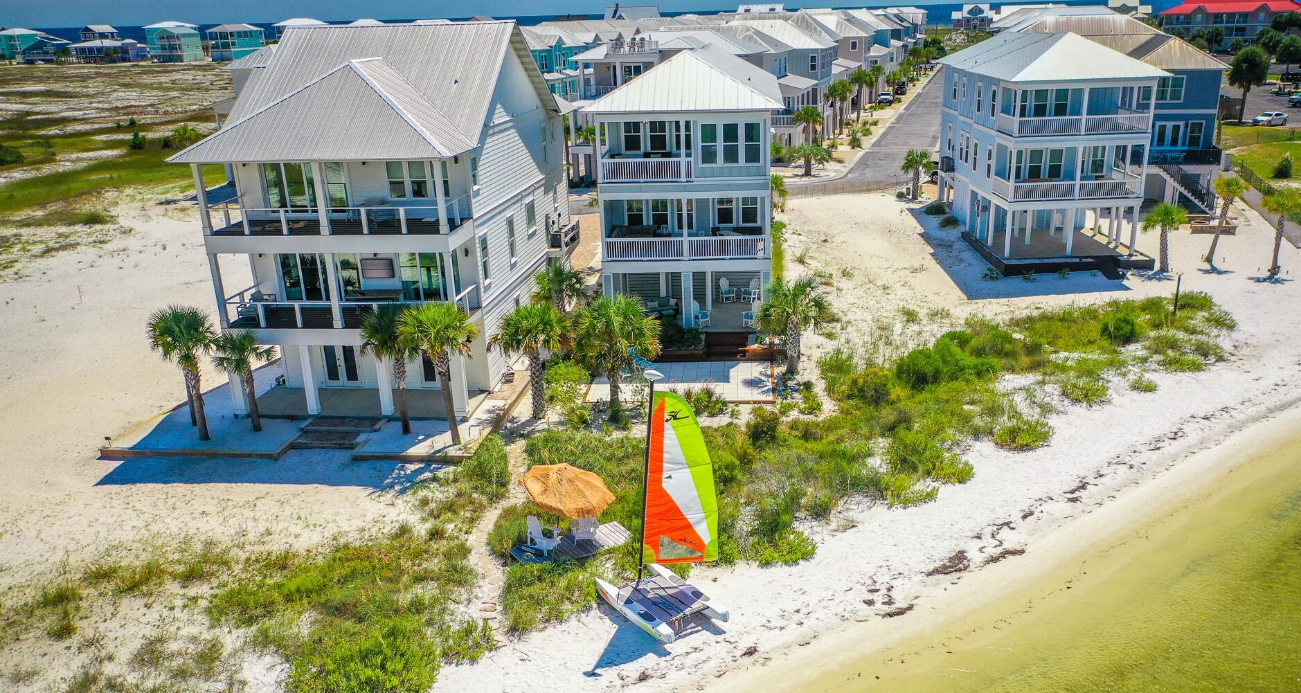 RESORT-STYLE ISLAND LIVING at its best in your beautiful customized waterfront home!  Whether you're looking for a SMART RENTAL INVESTMENT (We have a projection for $150,000 annually!)  that can house three families or a primary/secondary home, this luxury beach house is perfect! Located on the sugar white sandy beach of Santa Rosa Island, enjoy breathtaking water views of the Santa Rosa Sound from every window. You and your guests can go sailing at sunrise, jet skiing at lunch and paddle boarding in the afternoon with ease, as every recreation is right outside your back door! Paddle boards, fishing equipment and the Hobie Wave sailboat are all included.  Celebrate large family reunions around a fire on your enormous back patio surrounded by exotic palm trees and tropical plants. Spend unforgettable romantic evenings watching the spectacular sunsets from your balconies and fall asleep being serenaded by the gentle lapping of the waves outside your windows. Located in the highly sought after, gated "By the Sea" community, prepare for your guests to be impressed! This community has it all--pool, hot tub, friendly atmosphere, secluded beach and is only a five minute walk to the stunning emerald and turquoise waters of the Gulf of Mexico. The home has two oversized bedroom suites (each with a balcony) and two large guest rooms.  The home also has two gorgeous bonus spaces that are multi-purpose rooms currently used as offices but could easily be used as sleeping quarters. Furnishings, paddle boards, fishing equipment and the Hobie Wave sailboat are all included with the right offer.  Numerous media outlets and vacation companies have named Navarre Beach as one of the best and most beautiful beaches in the country. Don't miss out on the best decision you'll ever make. There's a finite amount of waterfront property, and most are not as magnificent as this one.  Make it YOURS before its too late.