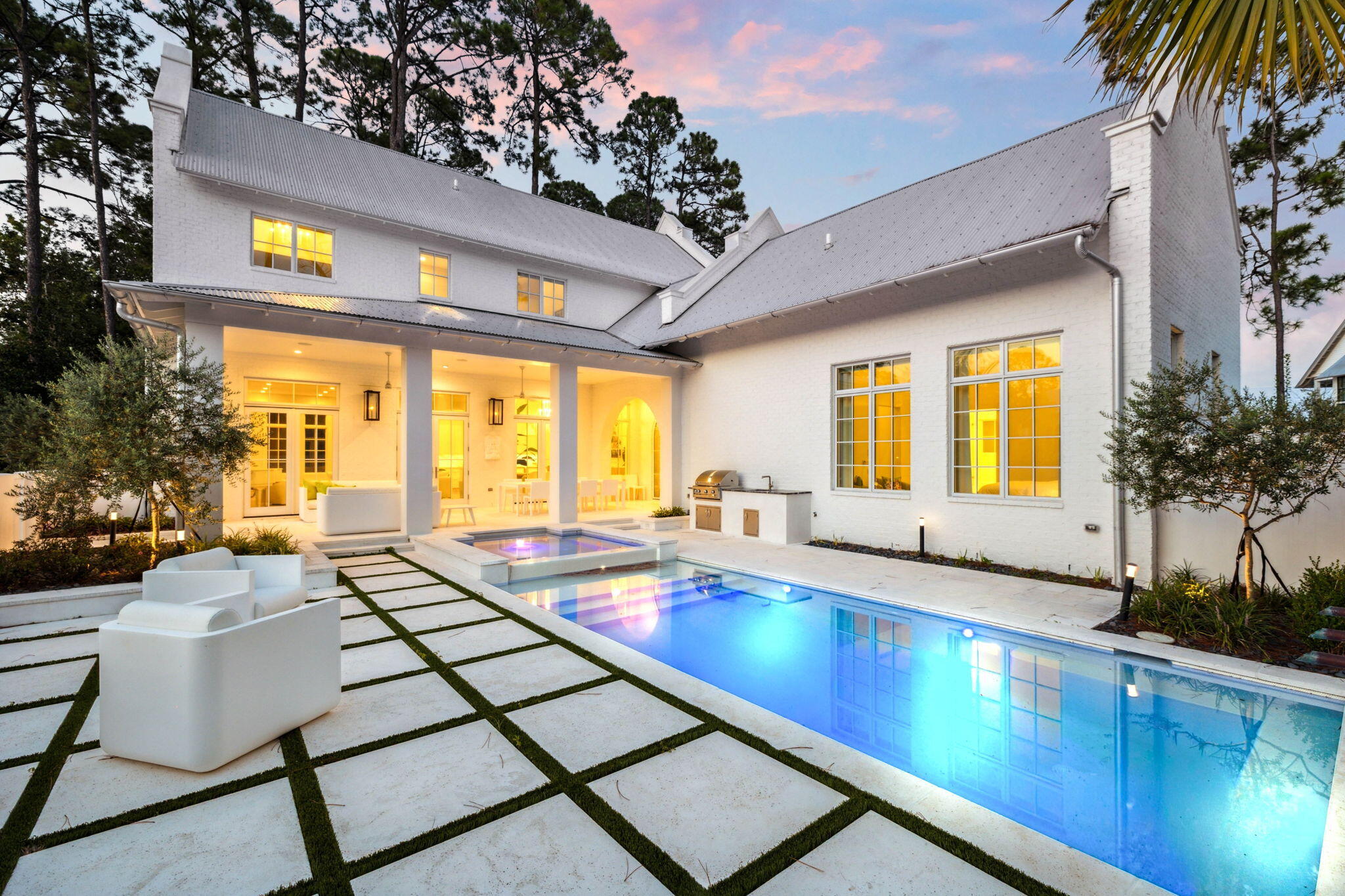 68 Perrin sits within the gated community of Churchill Oaks and offers a modern coastal design built around clean lines, natural light, and a functional layout that lives comfortably day to day. The home spans roughly 4,298 square feet with five bedrooms, five full baths, and two half baths arranged to balance openness with privacy.

The main living area feels refined without being overdone. Tall ceilings, expansive windows, and a marble-accented fireplace create a bright and inviting central space. The living, dining, and kitchen areas connect seamlessly, giving the home a sense of ease and flow. The kitchen features a waterfall-edge island, high-end appliances, and streamlined cabinetry that keeps the space crisp and uncluttered.

The primary suite is located on the main level... and is positioned to feel removed from the activity of the home. Vaulted ceilings and large windows bring in soft natural light, and the adjoining bath and custom walk-in closet reinforce a sense of calm and functionality. The remaining bedrooms are each en-suite and placed on separate wings or levels, offering comfort and independence for family or guests. Throughout the home, the layout feels intentional and well measured.

Outdoor living centers around a private courtyard that serves as an extension of the interior. A pool, spa, firepit, outdoor kitchen, and exterior half bath give the space structure and utility while maintaining a relaxed coastal feel. Access from multiple points of the home makes the courtyard a natural focal point. Two garages add convenience and storage.

Churchill Oaks is one of Santa Rosa Beach's most thoughtfully planned communities, set on more than 40 acres of preserved green space with mature oak canopy and sweeping views along the bay. Residents enjoy access to a private marina with boat slips, a waterfront clubhouse, fitness center, and a resort-style pool. The neighborhood's architectural standards, landscaped streets, and quiet setting create a cohesive environment that complements the design and quality of 68 Perrin.