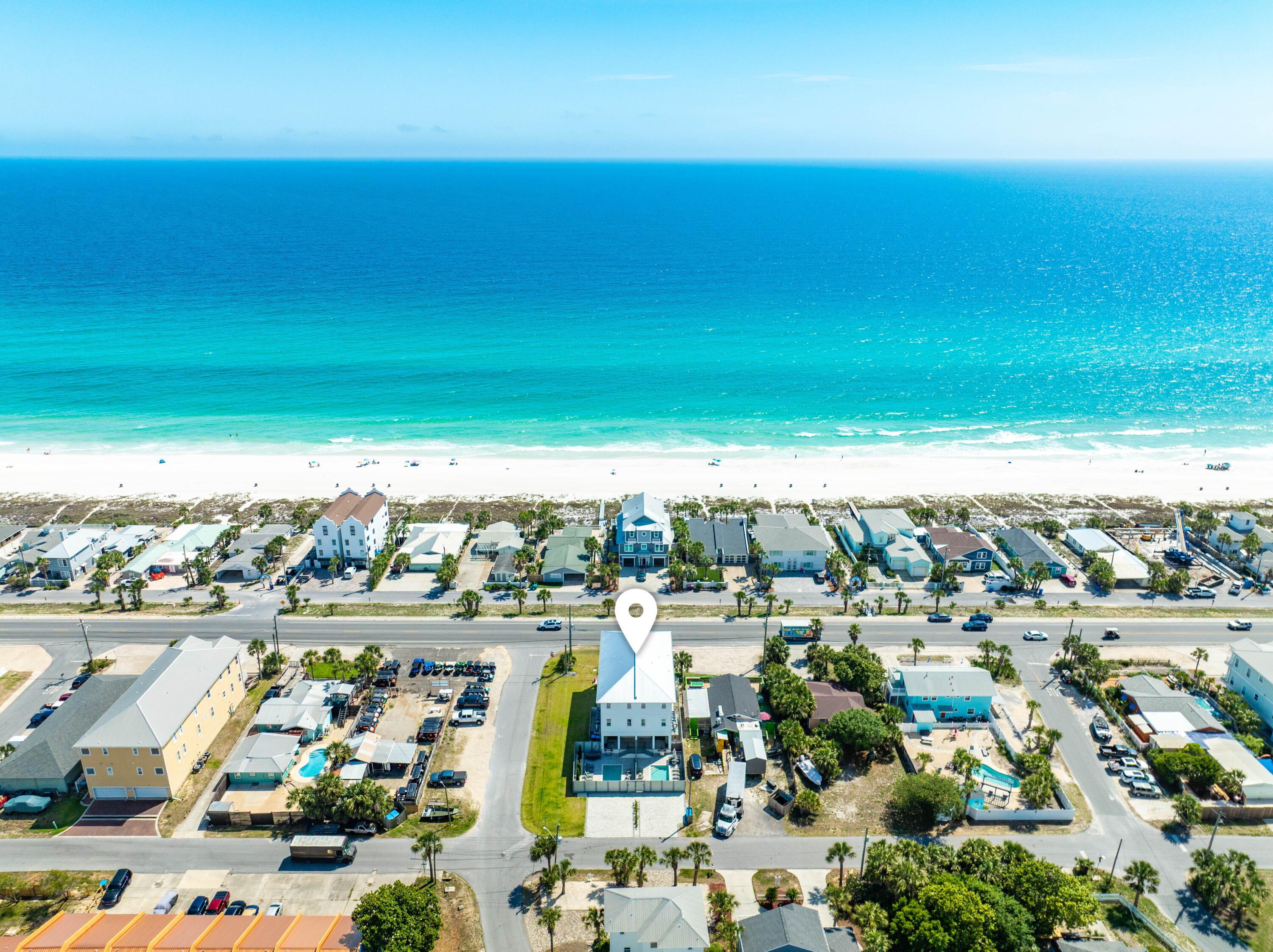 One of just two attached townhomes on Front Beach Road in Panama City Beach, this newly built three-story residence is offered fully furnished and turnkey, living entirely on its own -- a private entrance, a private fenced pool, and dedicated paver parking. It stands directly across Front Beach Road from the sugar-white sand and emerald Gulf, with two public beach accesses only a short walk away. Gulf views open from the main living level and the top-floor primary suite, and a private elevator serves all three floors.
The living level is anchored by a designer kitchen -- white shaker cabinetry, a quartz waterfall peninsula, premium stainless appliances, and a statement tile backsplash -- flowing into a generous dining area and a Gulf-view balcony made for sunset. One floor down, a dedicated game room with a pool table, air hockey, foosball, and a wet bar opens to the backyard, where a private pool and paver sun deck sit alongside an outdoor kitchen and grill.
Upstairs, the third-floor primary is a private retreat: a king suite with its own Gulf-view balcony, a spa-inspired bath in marble-look tile, a dual vanity, and a walk-in closet. Bedrooms on every level -- several with two beds, plus a children's bunk room -- welcome large groups with ease.
Just minutes from M.B. Miller Pier, Pier Park, and Topgolf -- a standout primary home, second residence, or Gulf-view investment in Panama City Beach. Set over three floors with nine-foot ceilings and wide-plank wood-look flooring, the layout keeps a full level of living between the entry and the bedrooms above.
On the ground floor, the recreation room opens to the fenced backyard and is served by a full bath, while a guest bedroom with ensuite bath, a spacious home office, and a second laundry room finish the level.
The middle floor gathers the open kitchen, dining, and living, with two more bedrooms and a powder bath positioned for guests.
The uppermost floor belongs to the primary suite, alongside two additional bedrooms, a full laundry room, and a wet bar just outside the suite.
By the pool, lounge seating and alfresco dining complete the fenced deck, and dedicated parking holds four vehicles.