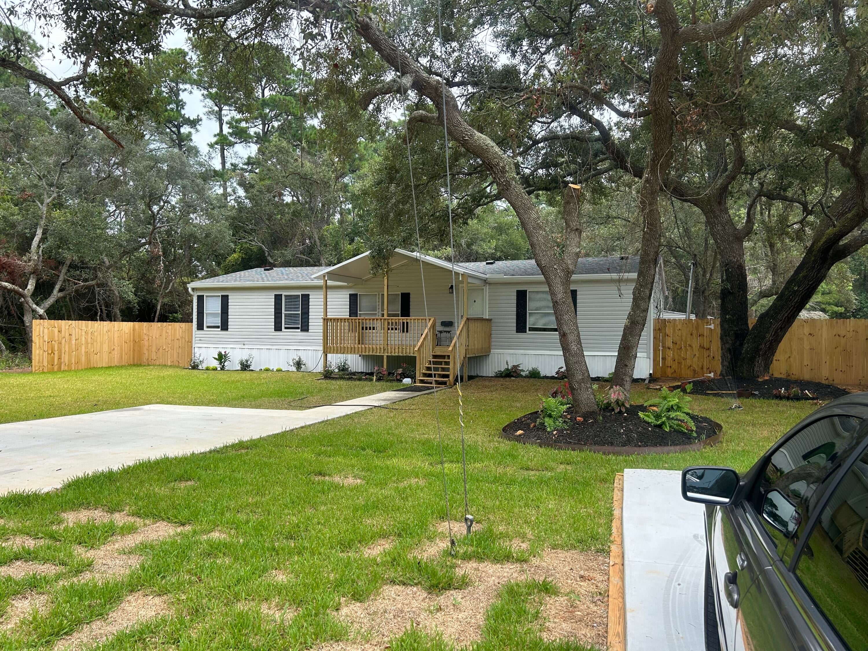 Welcome home to this charming **3-bedroom, 2-bath manufactured home** tucked away on a **secluded lot surrounded by beautiful, mature Live Oak trees** and conveniently located near the new **Soundside High School**. Step onto the inviting **front porch**, a perfect spot to relax and enjoy the peaceful setting. Inside, you'll find a functional **split floor plan** with **LVP flooring throughout** the home. The spacious owner's suite features a **ceiling fan, walk-in closet**, and private ensuite bath complete with a **double vanity, garden tub, and separate shower**.  Outside, the **fenced front yard** provides added privacy and space to enjoy the outdoors, while the backyard includes a **16' x 10' storage shed** for lawn equipment, tools, and additional storage.  Major updates include a **2023 roof** and **2022 HVAC system**, with the **water heater replaced in 2016**. With its peaceful setting, gorgeous Live Oaks, comfortable split floor plan, and convenient location, this home is ready for its next owner!
