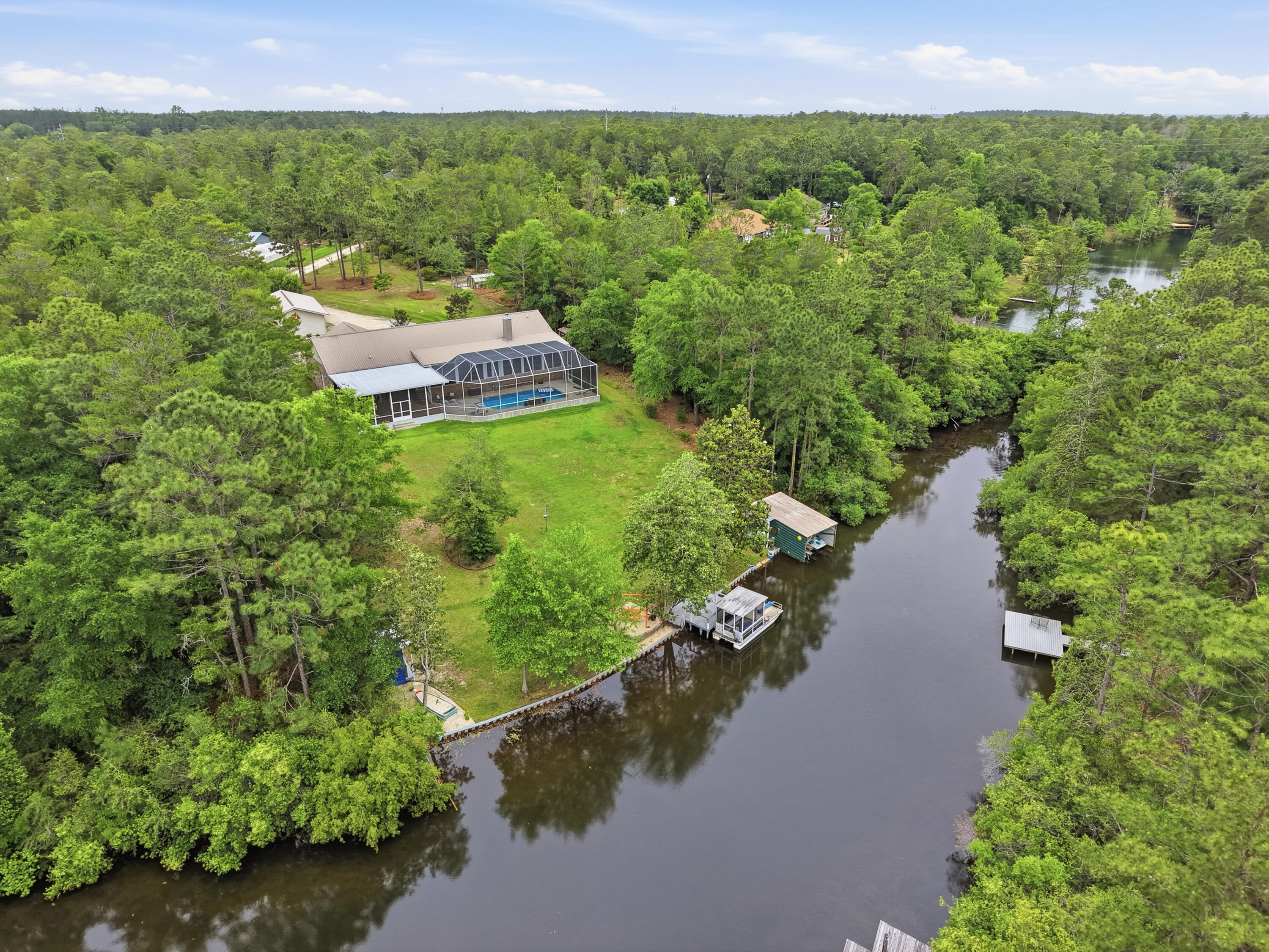 Contract pending with '72 hour Kick-out Clause' - taking back up offers. Peaceful lakefront living on beautiful spring fed Mirror Lake! This stunning home offers the perfect blend of privacy, comfort and outdoor living just 7 miles from town and close to military bases. Quiet country living without sacrificing convenience. Inside features a huge chef's kitchen, spacious living areas, and breathtaking lake views. Step outside to your private oasis with a heated screened swimming pool and beautiful cage enclosure overlooking the sparkling lake. The property includes a covered patio, large barn, RV pad with 50-amp hookup, irrigation system with pump house, greenhouse, orchard, and raised flower beds. Waterfront features include a boathouse, boats with kayaks included plus a dock. Watch the video & you'll see this incredible property truly has it all!