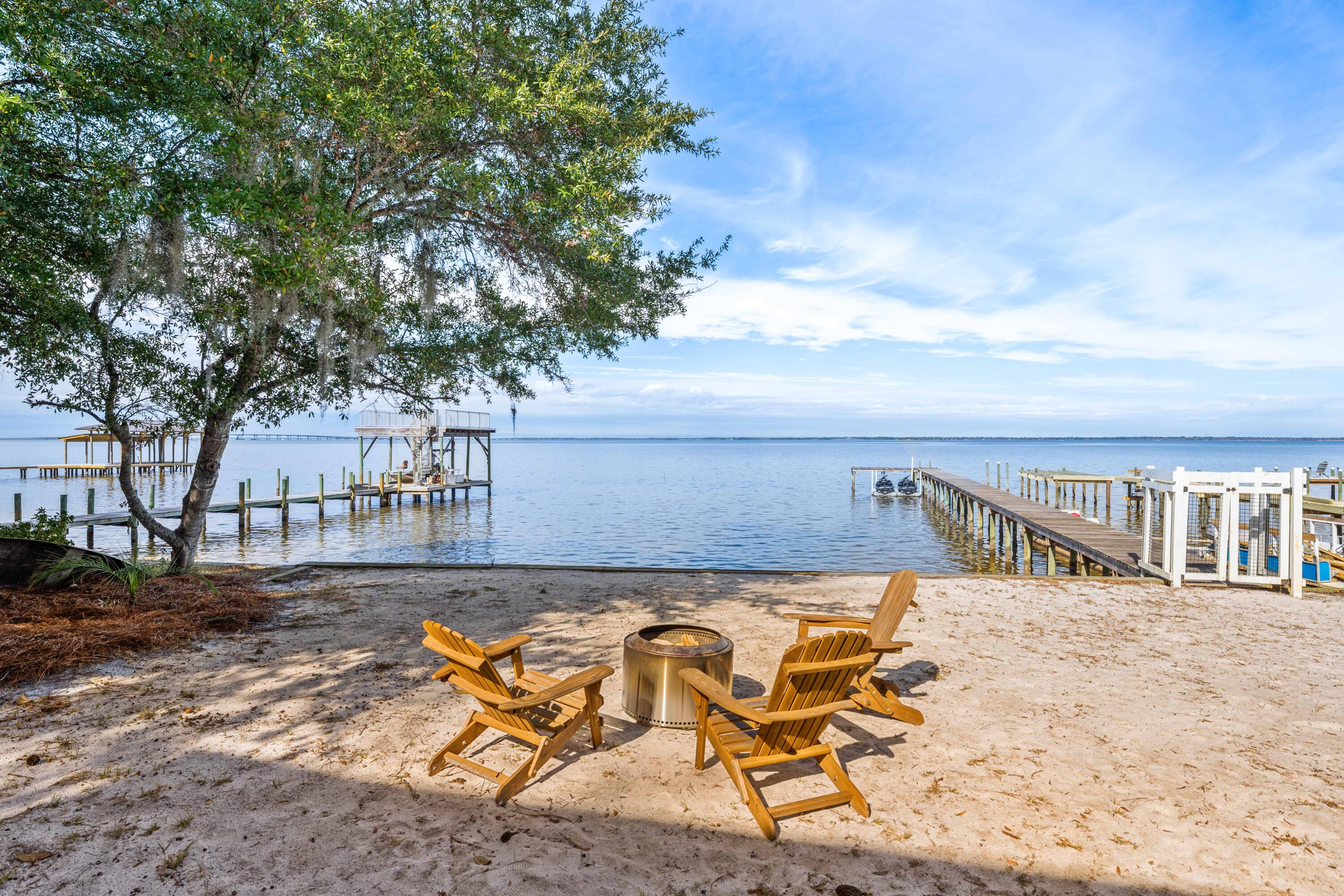 This contemporary 2-bedroom bay front bungalow is situated directly on Choctawhatchee Bay with direct water access and a private dock. The property features unobstructed views that stretch across the bay.

The concrete block construction and 20-foot hurricane-grade windows provide durability while framing water vistas from nearly every angle. The open-concept living space flows to outdoor areas featuring a 75-foot dock with bay access and a firepit overlooking the water.

The property includes generous storage and parking space for boats, kayaks, paddleboards, and recreational equipment. The modern kitchen and living area offer water views and a functional layout. Access fantastic dining, shopping and entertainment via water in Sandestin, the Destin Harbor, Saint Andrews Bay and more! 

Native Tree Lane is located in Santa Rosa Beach with proximity to the beaches of Grayton Beach, the shopping and dining destinations along 30A and Grand Boulevard, and the trails of Point Washington State Forest.