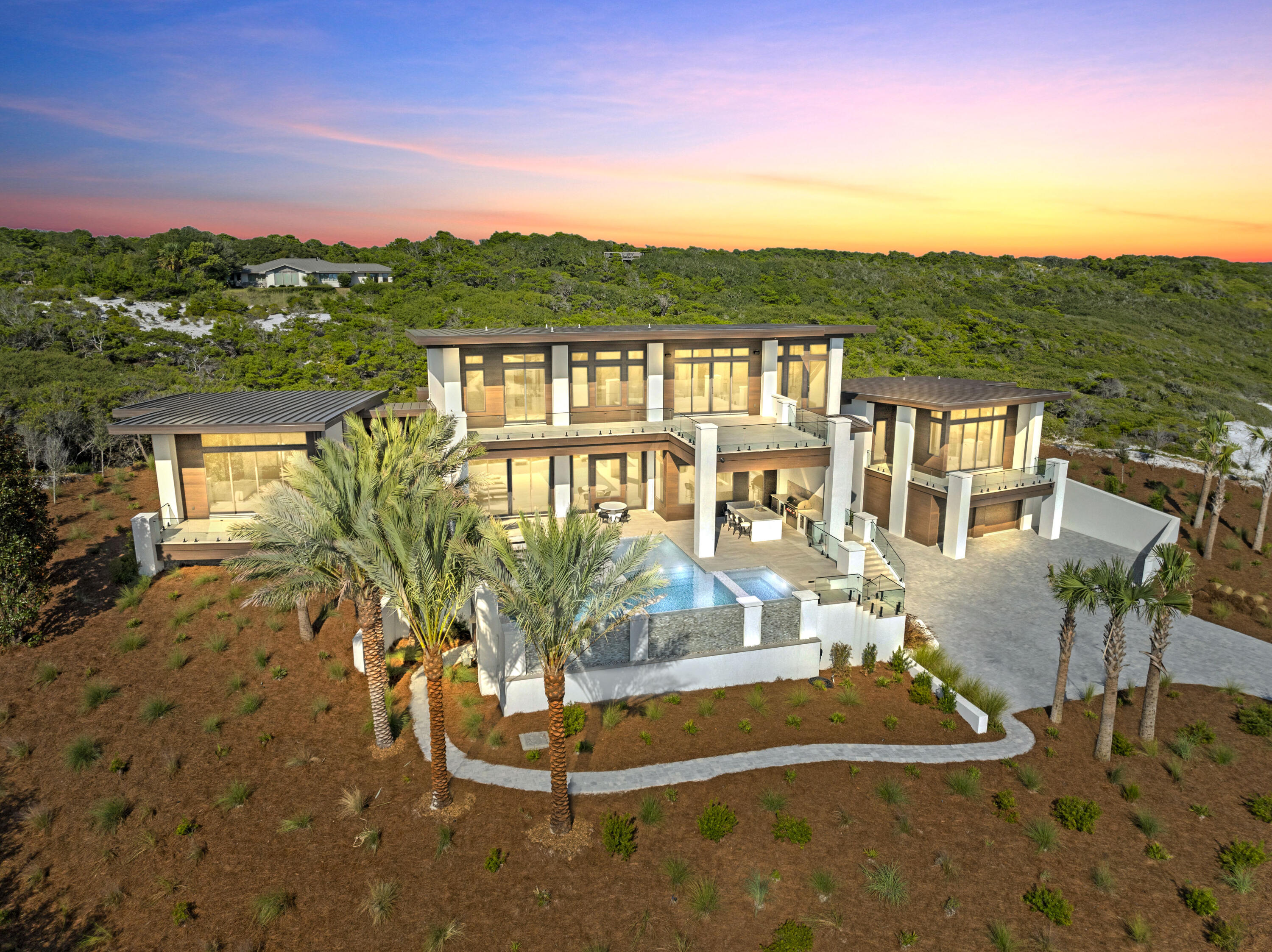 Experience the pinnacle of refined coastal living in Four Mile Village, one of the Emerald Coast's most secluded & prestigious gated enclaves. Perfectly positioned between the sugar-white sands of the Gulf and the untouched beauty of Topsail Hill Preserve State Park, this extraordinary contemporary estate offers an unrivaled blend of architectural significance, privacy, and panoramic Gulf views. This is more than a residence, it is a private Gulf-view sanctuary set upon a sprawling 1+ acre parcel, artfully designed for those who demand the exceptional. Encompassing 6,629 sq ft on a rare and commanding homesite just one row off the Gulf, this bespoke new construction masterpiece presents 5 bedrooms, 5 full baths, and 3 half baths, each space curated with uncompromising attention to detail. Designed by acclaimed architect Gregory D. Jazayeri and expertly built by the esteemed Castle Construction, the residence harmonizes mid-century modern principles with forward-thinking coastal design.
Clean architectural lines, stacked structural elements, and expansive walls of glass frame mesmerizing Gulf vistas while creating a seamless transition between indoor and outdoor living. An elevator services all levels of the home, providing effortless access throughout and enhancing both convenience and long-term livability. The open concept living, dining, and grand chef's kitchen serves as the heart of the home, offering uninterrupted Gulf views and seamless access to elongated outdoor terraces rarely found in coastal construction.

Two private primary wings anchor the main level, each a sanctuary of serenity and indulgence. Interior finishes and fixtures, masterfully curated by Kenneth Brown Designs, showcase thick-cut marble, heavy brass, crystalline glass, and bespoke detailing throughout. Both primary suites feature heated floors in the closets and bathrooms, elevating daily living to a spa-inspired experience.
The designer culinary space is appointed with a 48-inch dual-fuel range and a full suite of Sub-Zero and Wolf appliances, complemented by exquisite Waterworks Henry plumbing fixtures, where a single fixture can exceed $1.5K, alongside Henry door hardware and solid walnut interior doors, underscoring the home's commitment to superior craftsmanship. A C4 whole-house automation system provides intuitive control of lighting, climate, security, and entertainment.

The second level reveals 3 additional private ensuite bedrooms along with an expansive entertainment lounge complete with a wet bar and a convenient half bath, ideal for hosting with ease and flexibility.
Outdoors, natural vegetation creates a lush buffer of privacy to the north and south, while a heated and cooled infinity-edge pool with sun shelf overlooks both the Gulf and the community, offering breathtaking sunrise and sunset vistas.

Car enthusiasts and entertainers alike will appreciate the ample parking accommodations, including a 4-car garage and an expansive driveway with space for an additional 6 vehicles, an exceptional offering within this intimate coastal enclave.

Beyond the home, Four Mile Village offers a lifestyle that is increasingly rare. With fewer than 50 homesites, oversized Gulf-front and lakefront parcels, and height restrictions that preserve sightlines, the community maintains an atmosphere of timeless tranquility. Residents enjoy a private beach where miles of pristine shoreline often feel entirely your own, along with the rare coastal dune lake, Lake Fuller, and protected woodlands that enhance the enclave's natural beauty. Though secluded, the community is conveniently located just off Hwy 98, moments from premier shopping, dining, and resort amenities. Rich in history with roots tracing back to its World War II heritage, Four Mile Village remains a hidden jewel along the Emerald Coast where exclusivity, serenity, and architectural excellence converge.