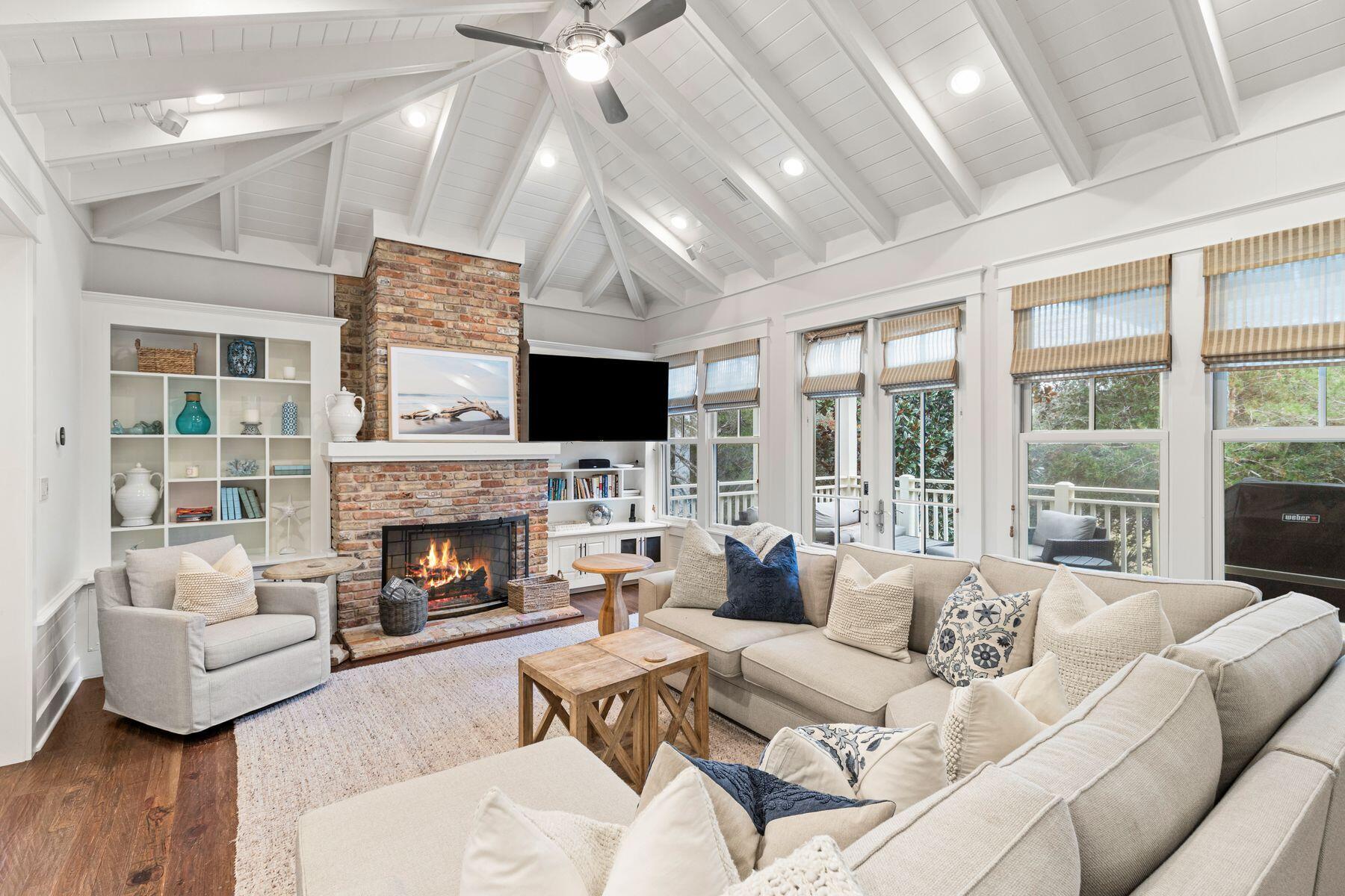 Just moments from the boardwalk and set in a remarkably private pocket of WaterSound Beach, this refined coastal retreat pairs serene dune and lake vistas with immediate access to community amenities. The setting is exceptional, framed by manicured green space at the rear, a pond across the street, and permanent views of Camp Creek Lake meeting the gulf's emerald horizon. Steps from the pool, outdoor lounge, and beach walkover, the home feels woven into its natural surroundings while offering the comforts of a full-time residence.

Crafted with classic architectural details inside and out, the four-bedroom main home and detached one-bedroom carriage house create a rare, versatile offering. Two primary suites in the main home accommodate multigenerational living, while the carriage house  complete with a full kitchen and private bath  welcomes guests with its own sense of retreat. Throughout the residence, rich hardwood floors, vaulted ceilings, and thoughtful built-ins elevate every space.

The upper-level great room rises beneath warm wood beams and opens to an expansive balcony where views stretch across dunes, lake, and gulf. A granite-clad kitchen with custom cabinetry, Viking appliances, and a breakfast bar anchors this gathering level, with a wet bar positioned nearby for effortless entertaining. A gas fireplace, recessed lighting, and coastal textures set a relaxed yet refined tone.

On the main level, the primary suite enjoys wooded privacy and a screened porch with a stairway leading to the upper balcony. Two additional ensuite bedrooms, including one flexed as a secondary living area, offer comfort for larger groups. The second-floor primary suite features soaring ceilings, gulf views, and a Juliette balcony perfectly placed for sunset.

The carriage house above the two-car garage provides a beautifully finished extension of the home, ideal for long-term guests or rental potential. With WaterSound Beach's gated security, private beach access, boardwalks, parks, and pools steps away, this beautifully maintained residence offers a prime location, a practical floor plan, and a setting that feels both rare and restorative.