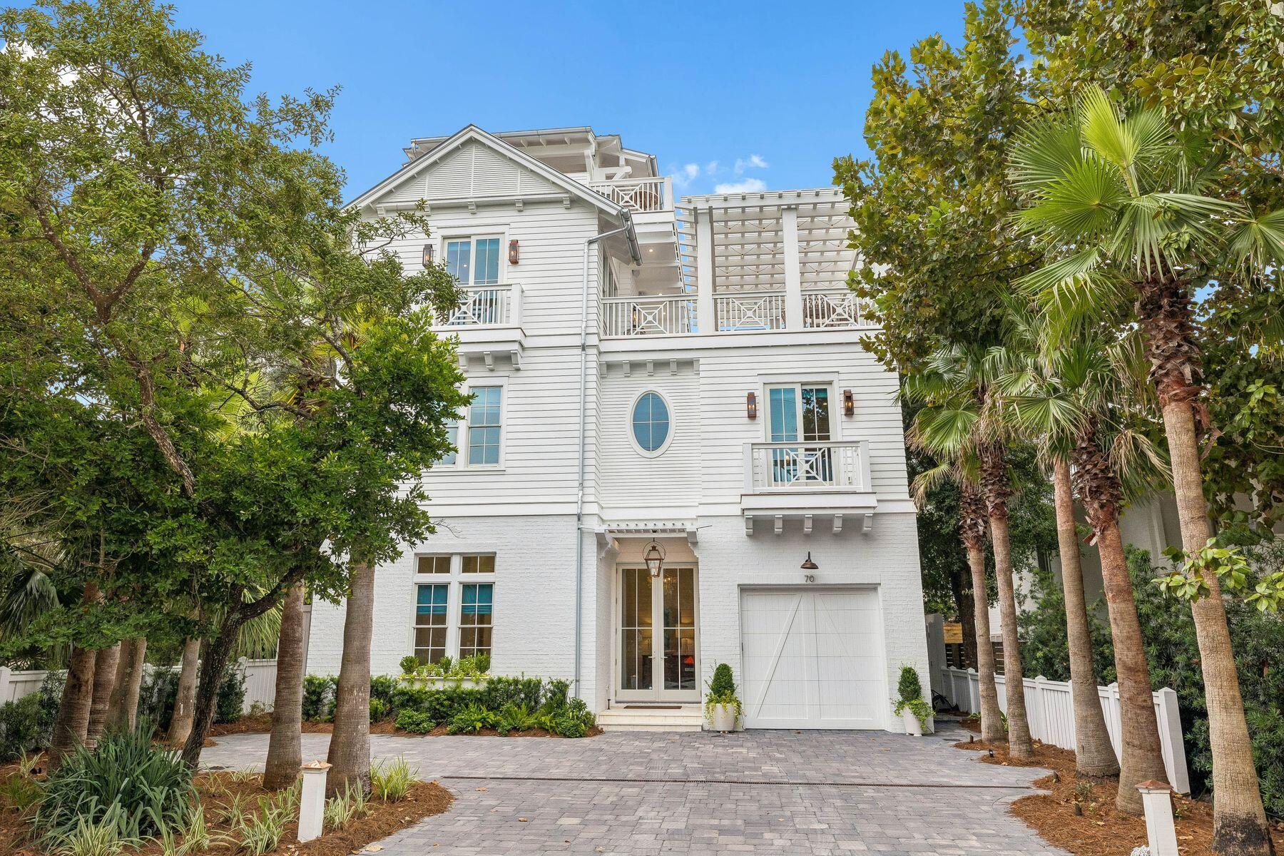 Less than 500 feet from the Dogwood-Thyme beach access and one street from Seaside, 70 Dogwood Street puts the best of Old Seagrove within an easy walk from the front door. A collaboration between the proven teams at Jazayeri Designs and LPKK Investments, this 2024 build has always served as a second home, never rented. The home offers six bedrooms plus a bunk room, eight full and one half baths, and 4,927 square feet of living space, with a one-car garage, generous parking, and no HOA. 
Gas lanterns frame a welcoming entry, setting the tone for the home's inviting feel and classic, elegant finishes. Inside, cypress ceilings, shiplap walls, shell stone and brick underfoot, and custom light fixtures set a warm, finely crafted tone that carries through the home. Wood floors run throughout the main level, and an elevator serves every floor including the viewing deck for gulf sunsets.
The kitchen is made for cooking together and gathering around. A large quartzite island anchors the room, with a farmhouse sink, a panel-front Sub-Zero refrigerator and freezer, and a Wolf range with griddle and pot filler beneath a Venetian plaster hood. A built-in Thermador coffee system makes mornings easy, and a hidden pantry keeps everything else out of sight. Floor-to-ceiling windows surround the dining area, and the living room, with its coffered ceiling and gas fireplace, is a natural place to settle in after a day on the beach. Open the full Nana wall and the living room flows onto a covered outdoor living area with its own fireplace and television, ready for game nights and evenings outside. The pool sits just beyond, shaded by mature trees, in a fully fenced backyard with a grill, a small lawn, and artificial turf, so there's room for everyone to play and relax. A bedroom with an en-suite bath and a wallpapered powder room complete the main level.
The second floor is anchored by the primary suite, a quiet retreat with a vaulted Venetian plaster ceiling, a gas fireplace, and a sitting area for slow mornings. The bath is finished in marble and grasscloth, with a freestanding soaking tub, a large shower, double vanities, a makeup vanity, a private water closet, and a walk-in closet. Two more king bedrooms on this level each have an en-suite bath, one finished in soft blue tile with a star-patterned floor. A dedicated office with its own full bath can serve as a seventh bedroom or a second bunk room when the whole family comes to town. A family room with a wet bar opens to a screened porch, and a wallpapered laundry room rounds out the floor.
The third floor is made for guests and kids. Two king bedrooms with vaulted ceilings each have an en-suite bath, and the bunk room, with extra-long twin-over-twin beds, has its own full bath. The bonus room, styled with a relaxed Palm Beach sensibility, opens to a generous pergola-covered deck, with plenty of seating and complete privacy among the treetops, close enough to hear the Gulf.
At the top of the home, a roughly 550-square-foot observation deck takes in views of the Gulf and the town of Seaside. With a refrigerator, ice maker, and television, it's a true living space, not just a lookout. The elevator opens directly onto the deck, making morning coffee and evening sunsets easy for everyone.
Days here begin with a short walk to the beach and end on the observation deck as the breeze comes in off the Gulf. Seaside's shops and restaurants are one street away, and the house is made for gathering, with room for everyone to spread out across four levels and come back together around the pool. Never rented and cared for as a private retreat, 70 Dogwood Street is ready for its next chapter of summers in Old Seagrove.
