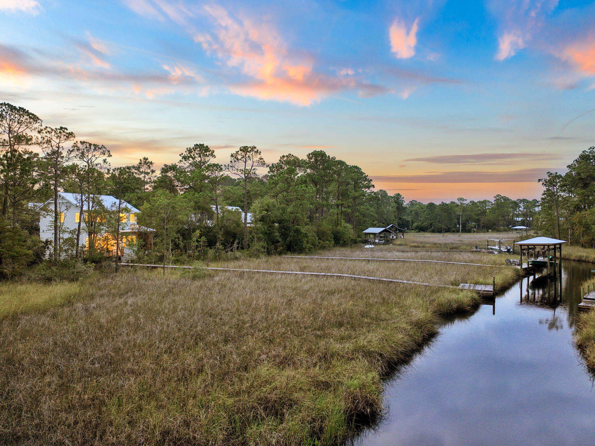 Tucked at the end of a quiet cul-de-sac in Magnolia Beach, this brand-new 3-bedroom, 2.5-bath waterfront retreat sits just minutes from 30A with 100 feet of frontage on the bay and bayou and a private dock offering direct boat access, ready for a lift. A wooden boardwalk winds through the marsh grass to the elevated home, setting the tone before you even reach the front door.

Inside, the open-concept main level is filled with natural light and framed by beamed, shiplap ceilings, wide-plank hardwood floors, and fireplace. The gourmet kitchen is built for entertaining, with custom cabinetry, quartz counters, a Thermador appliance suite including a dual-fuel range and double ovens, a pot filler, an oversized island with seating for five, and a walk-in butler's pantry with a second sink and prep space. The primary suite captures sweeping views of the bayou and marsh and features a spa-like bath with dual vanities, a freestanding soaking tub, and a glass walk-in shower. A screened porch and open deck extend the living space outdoors, overlooking the marsh toward the water.

Built in 2026 by an interior designer and custom builder team, the home showcases a striking A-frame silhouette, standing-seam metal roof, and board-and-batten siding, with custom moulding and thoughtful details carried throughout. Set on a 0.24-acre corner lot with a one-car garage and paver walkway, this is waterfront living at its finest - private, peaceful, and boat-ready.
