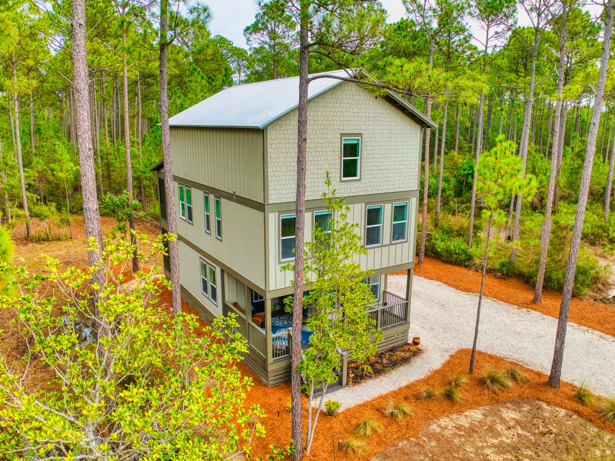 Welcome to 7537 Shady Glen Trail. Sitting on 0.62 acres, this three level home is ideal for a primary residence or second home with plenty of space to entertain. RiverCamps on Crooked Creek is located on the west end earning itself the title of Panama City Beach's hidden wooden oasis. The development sits on 1,500 acres, two thirds of that being devoted to conservation. The community has a zero-entry pool, approximately seven miles of interconnecting trails and boardwalks, boat launch and trailer storage, playground, pickle ball courts, designated campground space, west-end mailboxes, and the future fitness center is projected to open this Fall! Situated on the first floor is the main living space with a half bath and kitchen, equipped with LG electric range and KitchenAid refrigerator and dishwasher. Step through the sliding glass doors onto the screened in porch with an additional fridge, perfect for morning coffee and dinner parties. The second floor hosts the primary bedroom with direct access to a screened-in balcony, spacious bathroom with plenty of storage, and walk-in closet.  There are two other bedrooms on this level with opportunities to run them into a home gym or office. Conveniently located between the main bedrooms is the laundry area (LG WashTower Stacked Laundry Center). The third level has a second living area, full bathroom, and secondary primary bedroom. Within the bedroom is a hidden storage area with a door disguised as a bookcase for easy access to additional storage. RiverCamps is nestled on the north side of West Bay conveniently located: 10 miles from the beach; less than 15 minutes to NW Florida Beaches International Airport (ECP); FSU/TMH Medical Campus; Watersound West Bay Center along 79 (Publix projected to open in 2026); 45 minute boat ride to Shell Island; future Point South Marina West Bay.