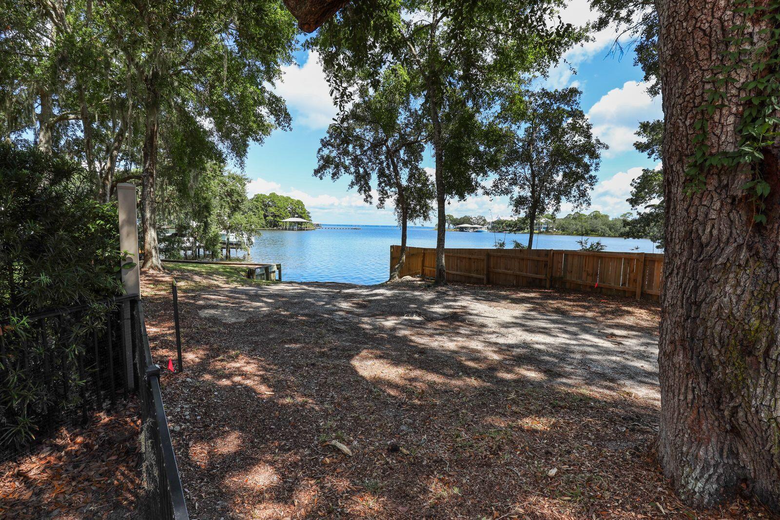 FULLY FURNISHED waterfront retreat home nestled in Sacred Oaks subdivision just off Mack Bayou Road.  Located close to Grand Boulevard shops, Sacred Heart on the Emerald Coast Hospital, Silver Sands Outlet and the beaches of Scenic Hwy 30A. Dining, shopping, and live entertainment is minutes away at The Village of Baytowne Wharf on the Sandestin Golf & Beach Resort. This 3-bedroom, 2.5-bath home features an open living, dining, and upgraded kitchen with plentiful bayviews. Large glider doors open to a spacious screened porch, patio, and backyard fire pit. Perfect for the outdoor enthusiast - with a boat dock & ramp next door. (No motorboats for noise control) Enjoy dolphins, coastal birds, spectacular sunrises and sunsets inside or outside. Home is located in the cul-de-sac and features a brick paver drive and parking, and is surrounded with mature trees and landscaping. Available for a 12 month lease. Don't miss out on this secluded gem with space for entertaining! An absolute treasure!