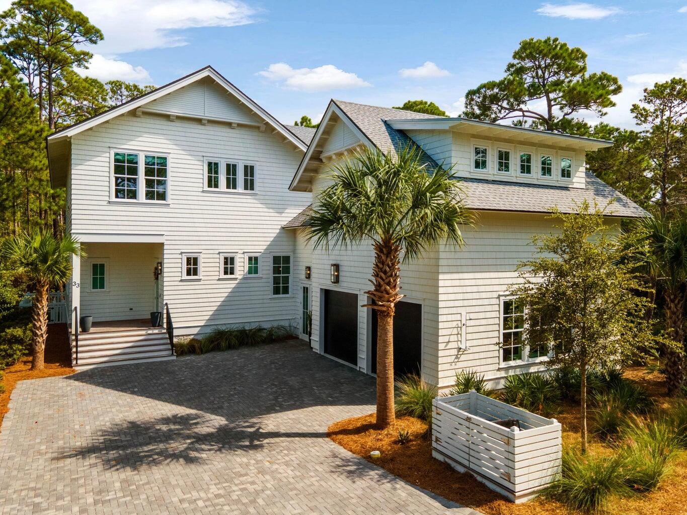 Tucked at the end of a quiet street in the gated enclave of Watersound West Beach, this custom coastal residence occupies one of the community's most private homesites. Protected natural preserve borders two sides of the property, including the entire pool and backyard, leaving no rear neighbor in sight. Just a short stroll down the community boardwalk brings you to deeded, uncrowded Gulf beach access bordering Deer Lake State Park, while 30A's boutique shopping and dining are an easy bike ride away.

Inside, five bedrooms and 4.5 baths unfold across two floors, including two primary suites, all beneath soaring vaulted shiplap ceilings and wide-plank hardwood flooring. The open-concept living and dining area is anchored by a chef's kitchen with a waterfall marble island, custom stone hood, and premium appliances. Walls of glass and folding accordion doors blur the line between indoors and out.

Step through to the screened porch, complete with a linear fireplace, mounted TV, swinging day bed, and outdoor kitchen -- an all-season gathering space overlooking the private pool and spa. One primary suite offers a true retreat with its own vaulted ceiling, a freestanding soaking tub, and a glass-enclosed walk-in shower. A charming built-in bunk room and additional guest suites offer flexible space for multigenerational gatherings, guests, or extended stays. A two-car garage completes the offering. This is coastal living distilled to its best elements: architectural craftsmanship, natural privacy rarely found this close to the beach, and a location inside one of 30A's most sought-after gated communities.
