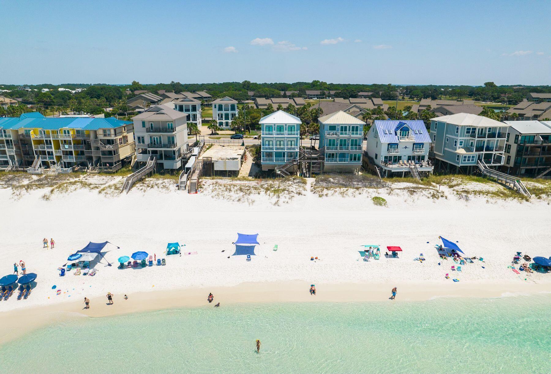Recently reimagined from the studs out, this gulf-front residence makes an immediate impression with three levels of south-facing deck space poised above the dunes and uninterrupted views stretching across the emerald water. Offered at an exceptional value for gulf-front ownership in the Destin and Miramar Beach market, the home pairs strong short-term rental performance with a setting that puts the beach quite literally at your doorstep. Paved parking for four vehicles provides easy arrival, while the first level is arranged for comfort and flexibility. Two gulf-front bedrooms open directly to the lower deck and beach path, creating an effortless connection to the shoreline. A media room with a wet bar and refrigerator adds a second living area for movie nights, game days or a private  retreat for younger guests. The layout also includes a king bedroom, a bunk room and thoughtful family-friendly touches throughout, including a private dog cove for pets up to 25 pounds. On the second floor, walls of glass frame sweeping 180-degree gulf views from nearly every angle of the main living space. The family room and dining area open to an expansive balcony through three sets of French doors, setting the stage for sunset cocktails, morning coffee and long afternoons with the sound of the waves in the background. Just beyond, the open kitchen is outfitted with stainless steel appliances, custom cabinetry, granite countertops and a generous breakfast bar designed for casual gathering. A nearby half bath adds convenience to the main entertaining level, while a fully equipped home theater with projection TV elevates the experience for guests and owners alike. The third floor is reserved for a more private coastal escape. The gulf-front primary suite is a true sanctuary, with panoramic water views and an updated bath featuring dual vanities, a freestanding soaking tub and a walk-in shower. Two additional guest rooms, including a bunk room, are served by another full bath and offer ample accommodations for family and visitors. With no HOA, recent full-scale renovations, a new roof and projected annual income of $275,000, this five-bedroom property stands out as a proven investment and an inviting personal retreat. Shopping, dining, golf and entertainment are all close at hand, including Silver Sands Outlet Mall, yet the true luxury here is the rare simplicity of having the beach just beyond your deck and gulf views that carry on for miles.