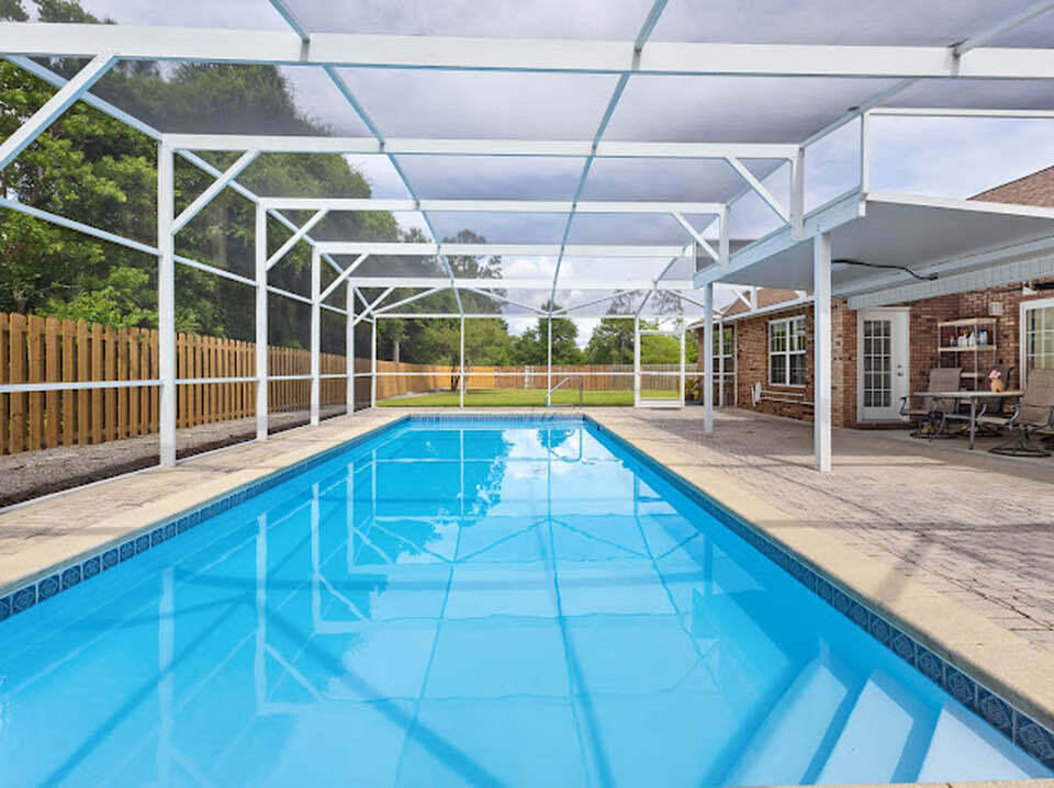 Welcome to your private slice of Florida paradise in desirable Lynn Haven. This beautifully refreshed pool home offers space, privacy, and thoughtful updates, all tucked away on a generously sized lot backing to a natural wooded setting with no rear neighbors. Step inside to soaring ceilings, abundant natural light, and an airy open concept layout designed for comfortable everyday living and effortless entertaining. Fresh interior paint gives the home a crisp, move in ready feel, while spacious living areas flow seamlessly into the kitchen and out to the backyard retreat. The kitchen features stainless steel appliances, abundant cabinetry, generous prep space, and a functional layout overlooking the main living area and pool, keeping everyone connected. A formal dining or flex space at the front of the home offers versatility for entertaining, a home office, or additional sitting area. The oversized primary suite is a true retreat with dual vanities, a soaking tub, and a beautifully renovated spa inspired walk in shower with designer tilework and modern finishes. Out back is where this home truly shines. Enjoy your oversized screened private pool enclosure with a sparkling in ground pool, expansive patio space, and the privacy buyers dream of. The large fenced backyard offers room for pets, play, or gardening. As an added bonus, residents also enjoy access to a community pool.
Additional highlights include a spacious laundry room, storage shed, vaulted ceilings.