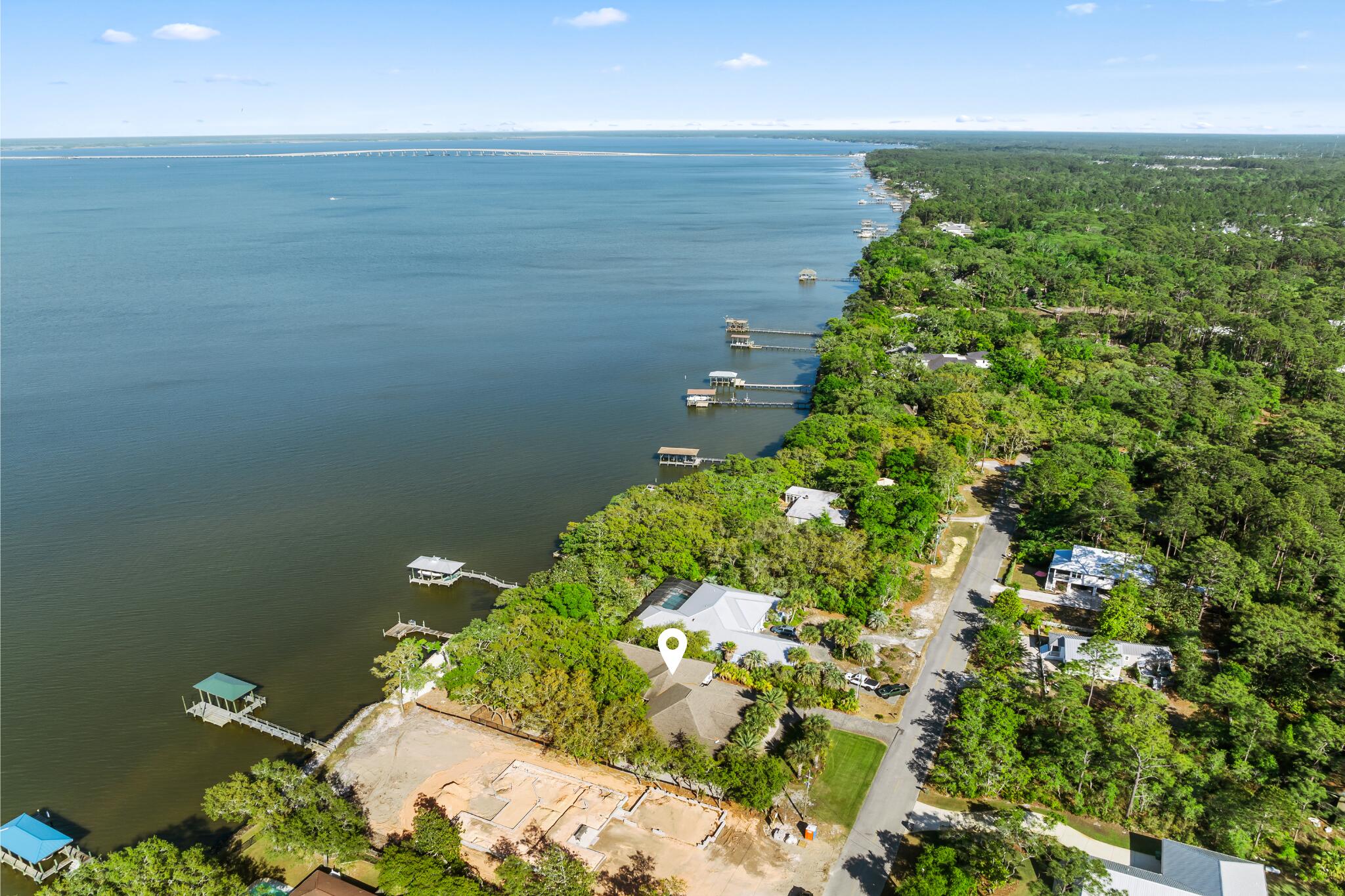 A rare chance to own on the water in Santa Rosa Beach's established Hatchee Shores community. This nearly half-acre homesite delivers 100 feet of bay frontage and a private dock with unobstructed open-bay views, making it the kind of setting made for boating, fishing, or simply watching the sun go down.

The home itself spans 3 bedrooms and 3 bathrooms across a well-maintained, light-filled floor plan built for easy coastal living. Mature palms shade the home's stone-accented façade, while a brick paver driveway and double glass entry, flanked by stone columns, set an elevated first impression.

Inside, hardwood and tile flooring flow throughout, complemented by crown molding and a stacked-stone fireplace that anchors the great room. The primary suite offers a spa-inspired bath with soaking tub, dual vanities, stone counters, and a walk-in tile shower.

Outdoor living is equally impressive: a covered back porch beneath grand live oaks, an outdoor shower, carport, and attached garage, plus a detached workshop/storage building for gear, hobbies, or extra storage.

Whether you're seeking a full-time residence, a second home on the water, or an income-producing property, this one checks every box, and it's all just minutes from 30A's sugar-white beaches, top dining, and boutique shopping.