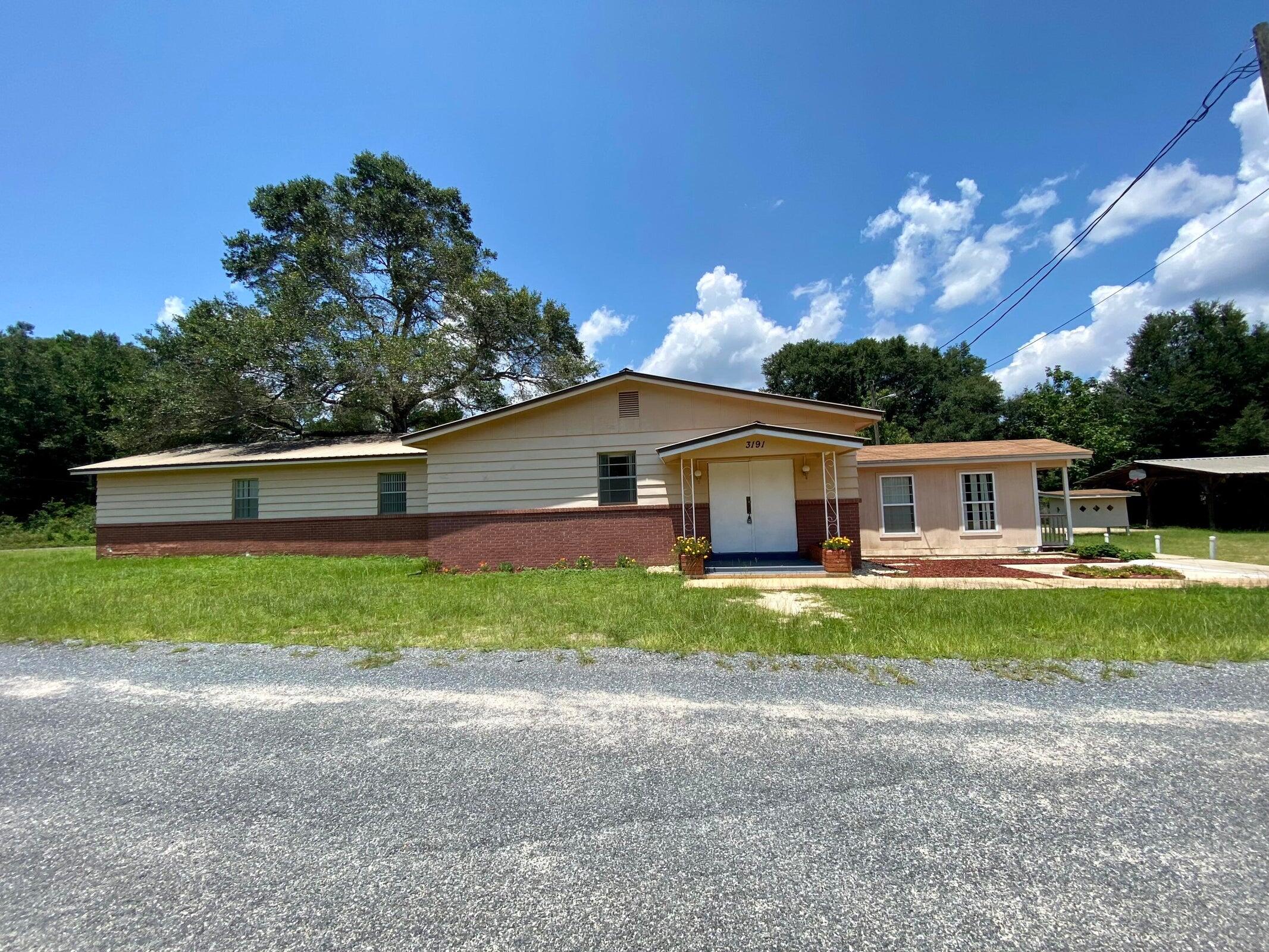 Currently utilized as a church, the property features a flexible interior layout with a spacious main gathering area, multiple additional rooms, and a kitchen with pass-through window. Two restroom facilities are on site; however, a tub or shower would need to be added for traditional residential use. Exterior features include two enclosed storage outbuildings, a paved recreational area currently set up as a basketball court, and a covered seating area. Buyer to verify zoning, land use, and intended use suitability.'