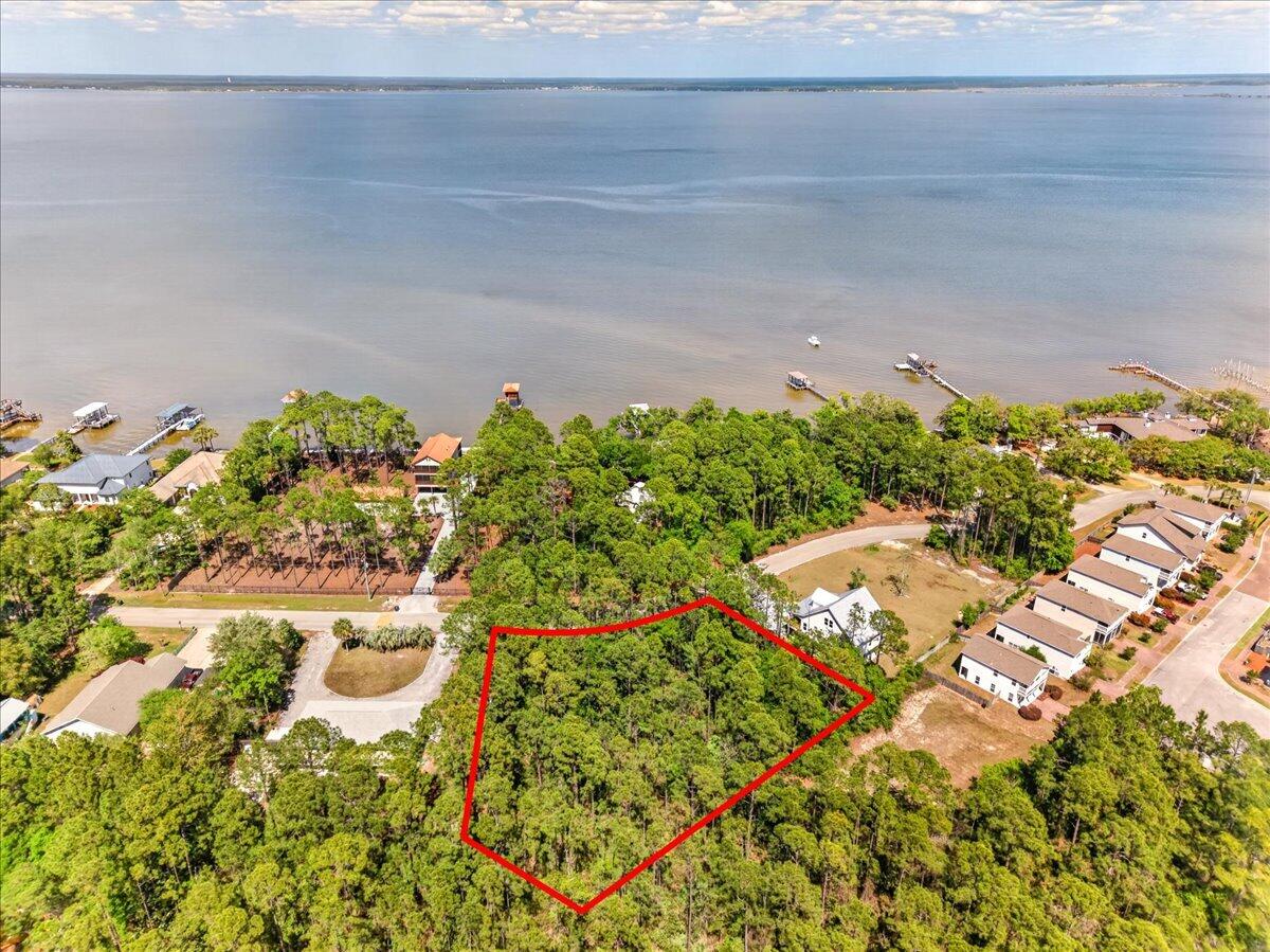 This wooded corner lot offers a beautiful setting to build your future home, with Choctawhatchee Bay directly across the street! Surrounded by natural landscape, the property provides a peaceful, coastal feel while still being conveniently located. With no HOA, you have the flexibility to design and build to suit your vision without restrictive guidelines. This lot sits in a quiet, well established neighborhood - perfect for families! Utilities including water, sewer, and power are available, and a survey is already on hand. Enjoy multiple Gulf beach accesses all within a 15 minute drive (Blue Mountain Beach, Ed Walline, and more)! Kellogg Bayside Park is just 0.2 miles away, offering easy bay access for kayaking, paddleboarding, and canoeing, along with a fishing area, picnic tables, and an outdoor shower. Just 1.6 miles away, Cessna Landing features a public boat launch, docks, picnic shelters, basketball and squash courts, and a playground. Convenience meets location with South Walton Publix, dining, and everyday essentials only minutes away. Situated just north of Chat Holley Road and Highway 98, this property offers easy commuting while keeping you close to the water and all the area has to offer!