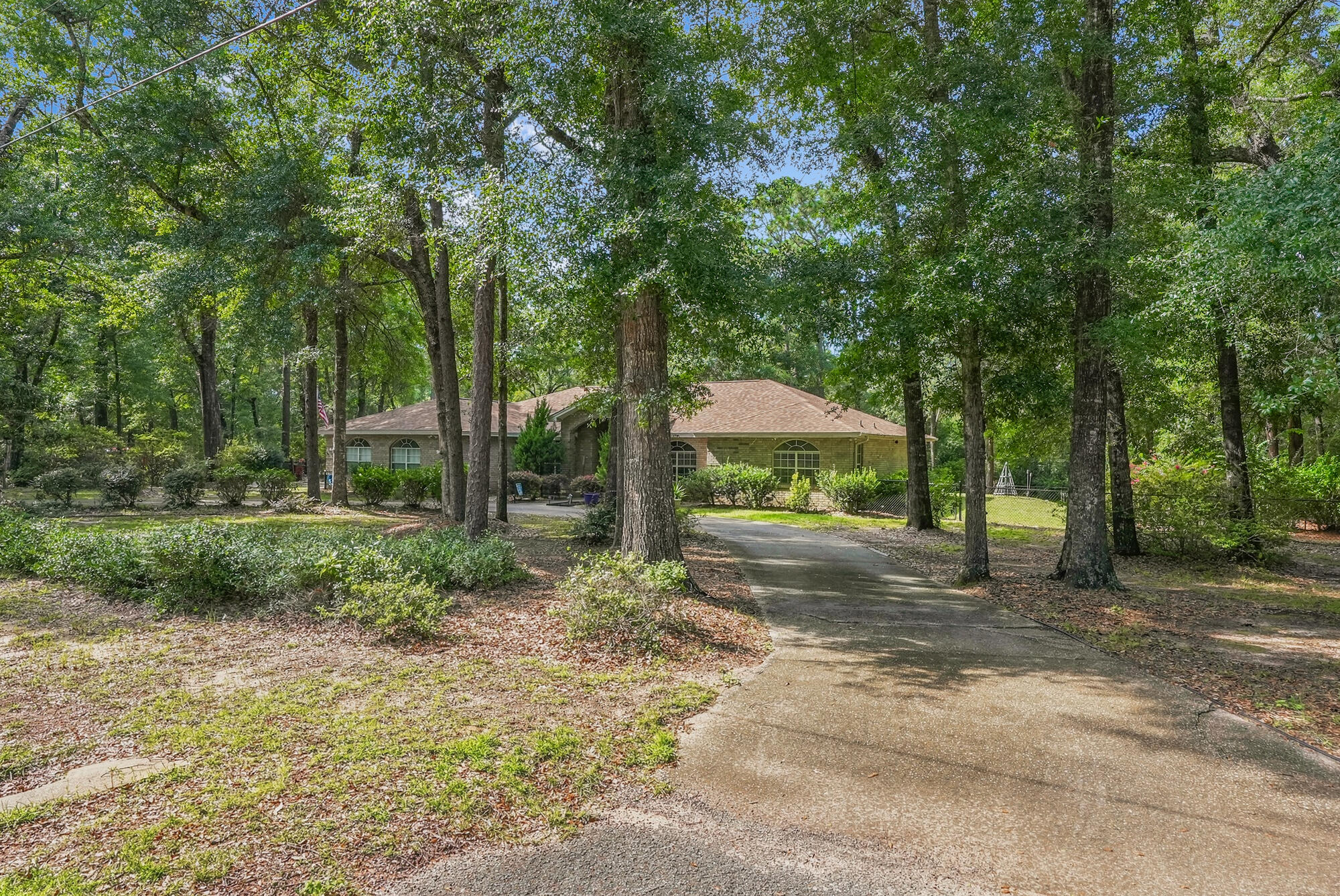 A true legacy property, 6932 Summit Place in Wildwood Estates offers three private acres (residing over 3 lots), remarkable versatility, and the freedom of no HOA. A stately U-shaped driveway, along with a separate garage drive, creates an impressive approach to the charming façade, framed by lush landscaping and a canopy of mature trees.

Inside, the sprawling 2,700-square-foot home welcomes you with abundant natural light, soaring ceilings, and new luxury vinyl plank flooring. Designed for comfortable everyday living and effortless entertaining, the main living area features a gas fireplace, while the sunroom provides a peaceful place to enjoy views of the picturesque foliage. A second living space--with a pool table that conveys--offers another inviting setting for relaxing and gathering.

The spacious kitchen features shaker-style cabinetry, a new appliance package, and a pantry, with a formal dining room and interior laundry nearby. Two generously sized guest bedrooms are located on this wing. Just off the entertainment room, a spacious junior suite includes a dedicated office nook and access to an adjacent half bath. Bright and airy, the primary suite offers beautiful views of blooming camellias, private sunroom access, and a shaded covered back porch. The spa-inspired ensuite includes an extended vanity, oversized soaking tub, separate shower, private water closet, and dual closets.

Outdoors, the property unfolds into a serene retreat across three acres. Features include two storage sheds, a converted outbuilding equipped with air conditioning, a television, and bunks; winding trails; three separate gardens; and a new aluminum fence--an approximately $20,000 investment--enclosing the first two acres.

Recent improvements include a new HVAC system installed in 2023, a new water heater in 2024, a roof installed in 2022, a new kitchen appliance package, updated light fixtures and flooring, window treatments, plus extensive landscaping and clearing. With its space, privacy, thoughtful updates, and endless possibilities, this one-of-a-kind Wildwood Estates property is ready to welcome you home. Inquire today and start living the lifestyle you deserve.