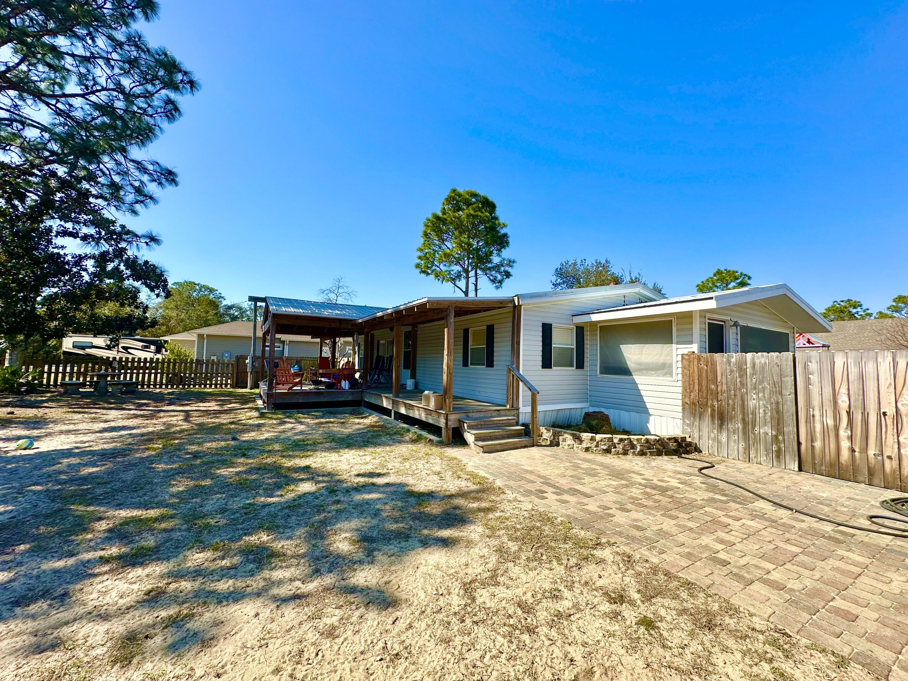 $5,000 to Buyer at closing! Set in a highly desirable, fast-growing neighborhood surrounded by attractive new construction, this property offers both comfort and long-term value in a well-connected area with convenient access to beaches, 30A, schools, shopping, dining, and everyday amenities. With 1,215 square feet of updated living space this 3 bedroom, 2 bath manufactured home sit on a spacious 0.27 acre lot with fenced front and back yards Built in 2002 with the addition of a sizable covered front porch creates a comfortable outdoor gathering space. The metal roof is approx. 10 years, and AC replaced about 6 years ago. Remodeled kitchen and baths elevate the space along with an 800 square foot detached garage/workshop with the additional storage space. Schedule a private showing today!